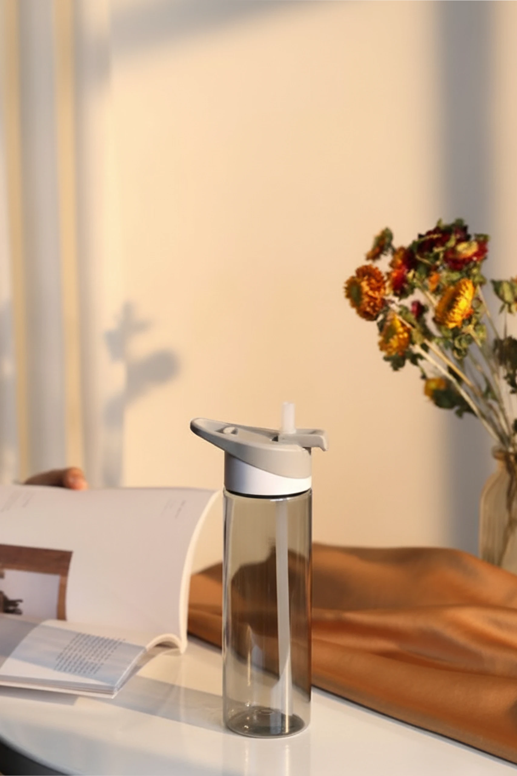 Botella de gimnasio personalizada LEMOS Botella de gimnasio gris sobre una mesa y un libro abierto