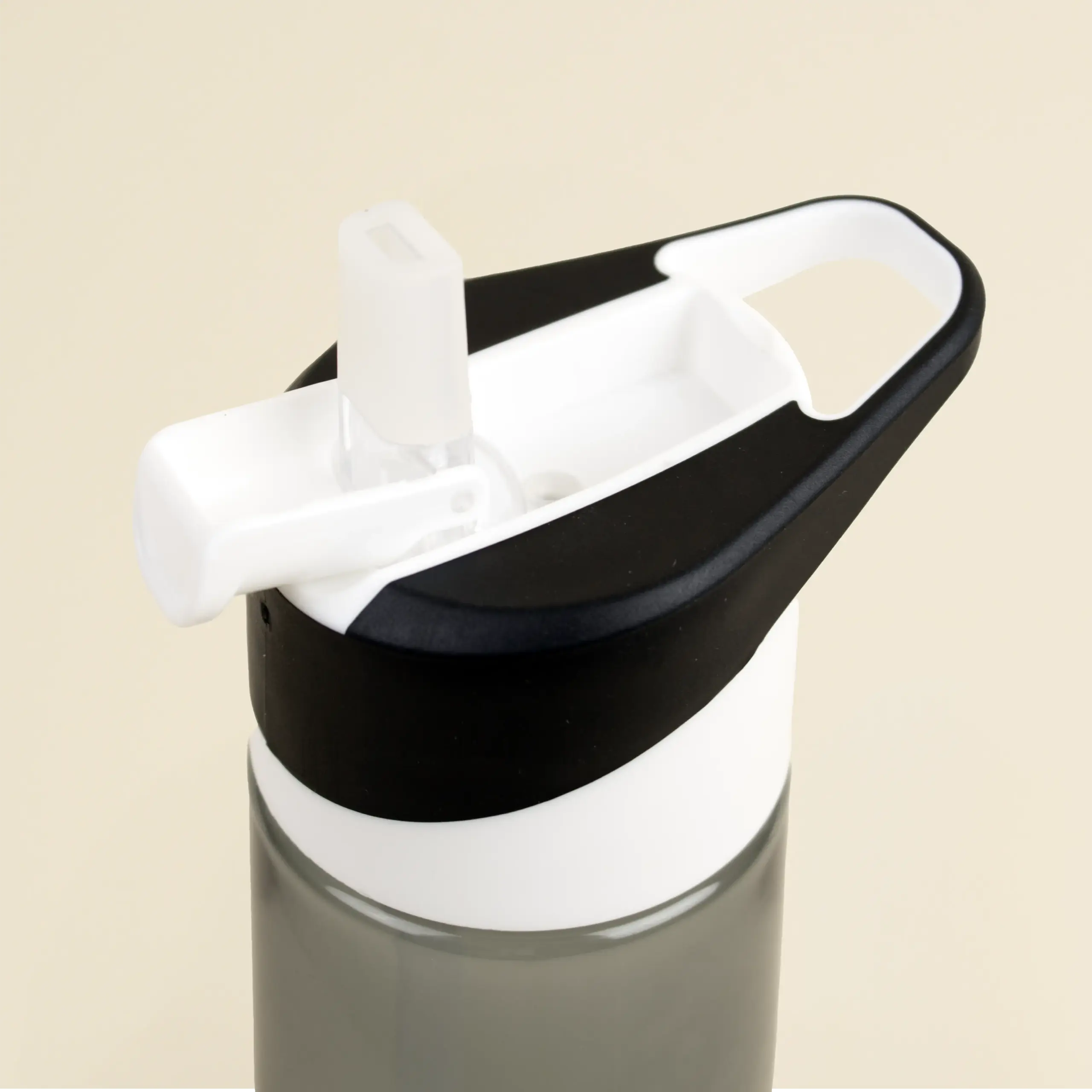 Botella de gimnasio personalizada LEMOS Boquilla de una botella de gimnasio negra sobre un fondo beige