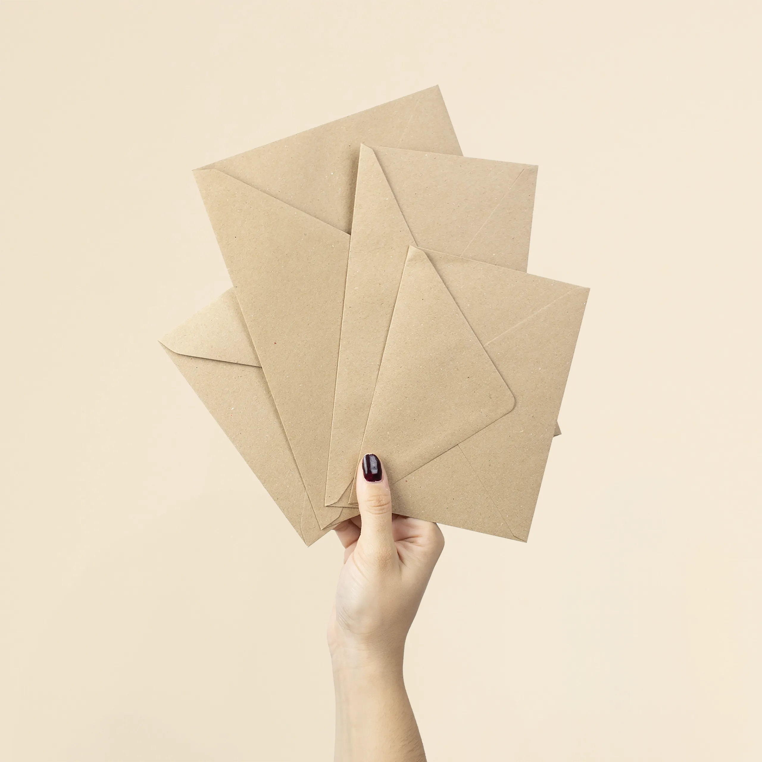Sobres kraft personalizados FAMILIA Mano sujetando cuatro sobres kraft de diferentes tamaños