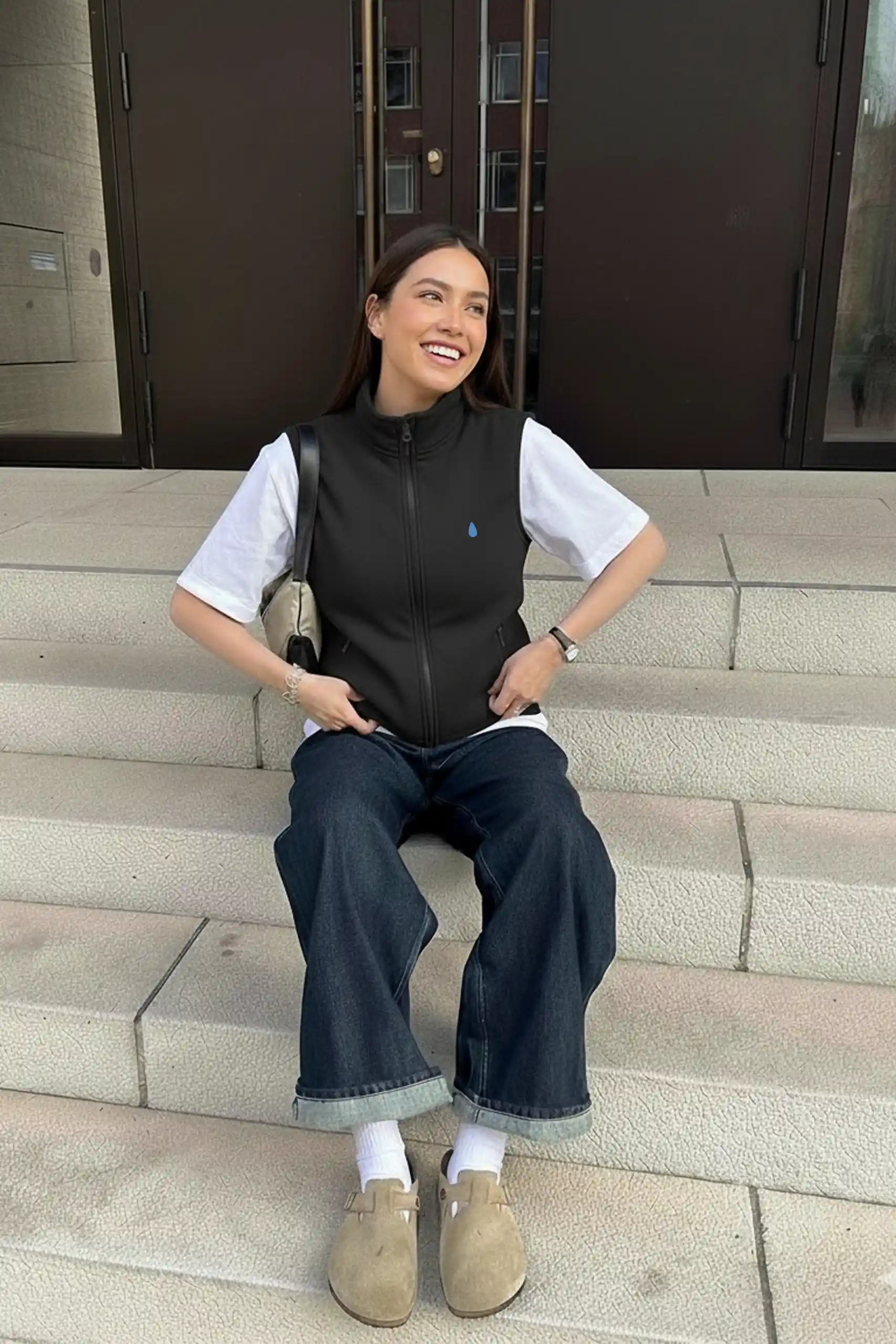 Chica con Chaleco polar personalizado negro con cremallera sentada en unas escaleras