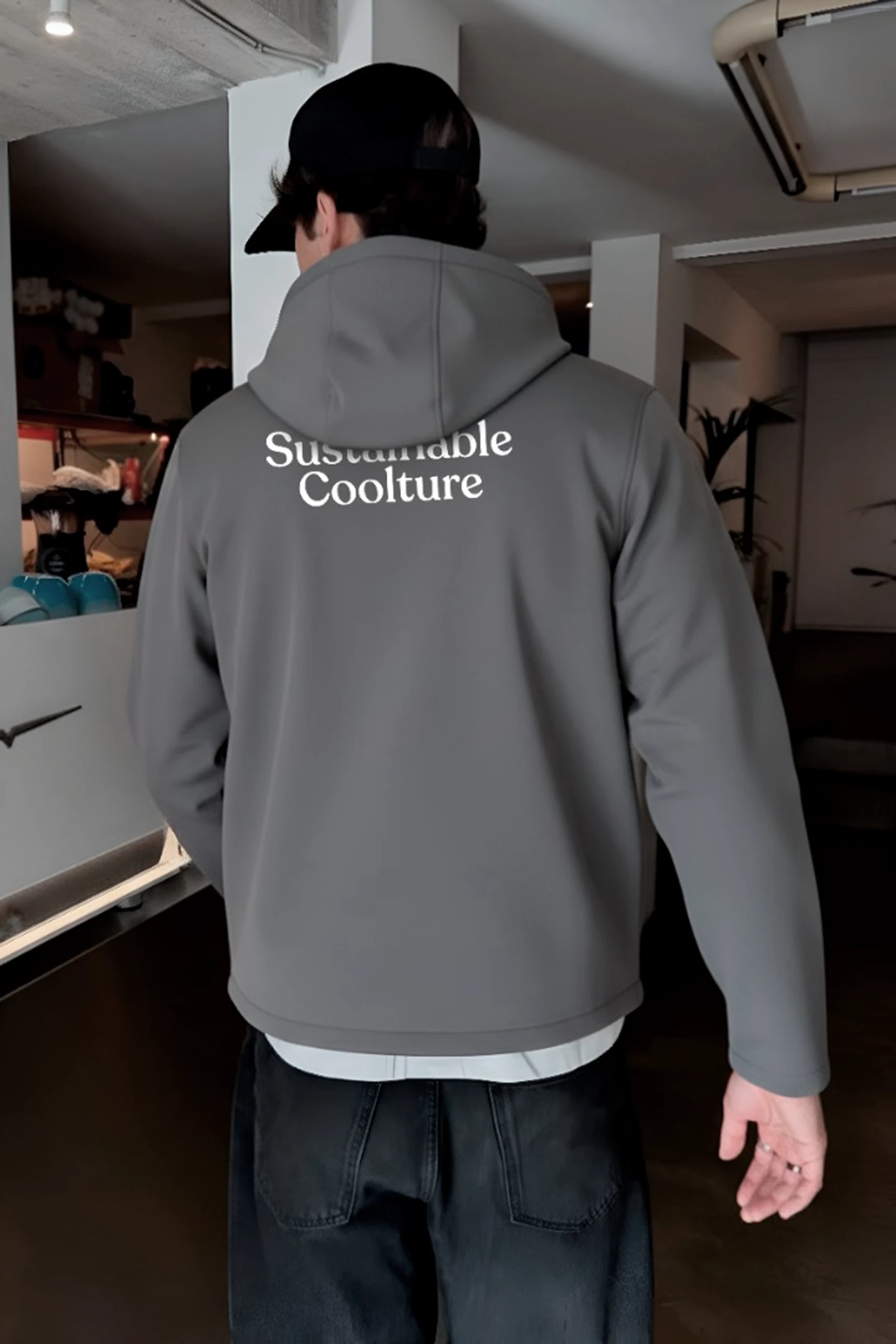 Chico de espaldas con chaqueta personalizada gris con capucha en una cafetería