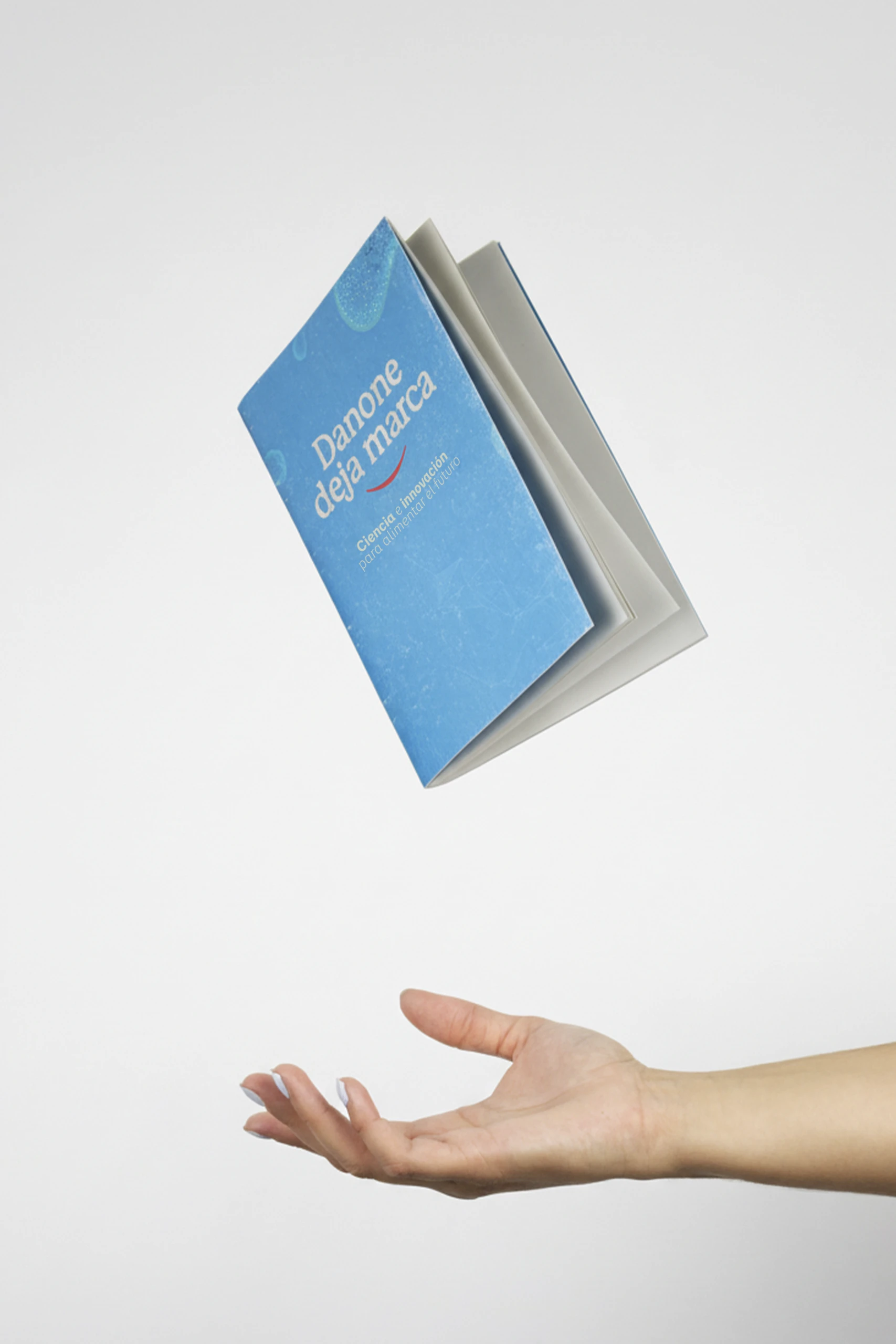 Cuaderno ecológico impreso a todo color de Danone con una mano levitando