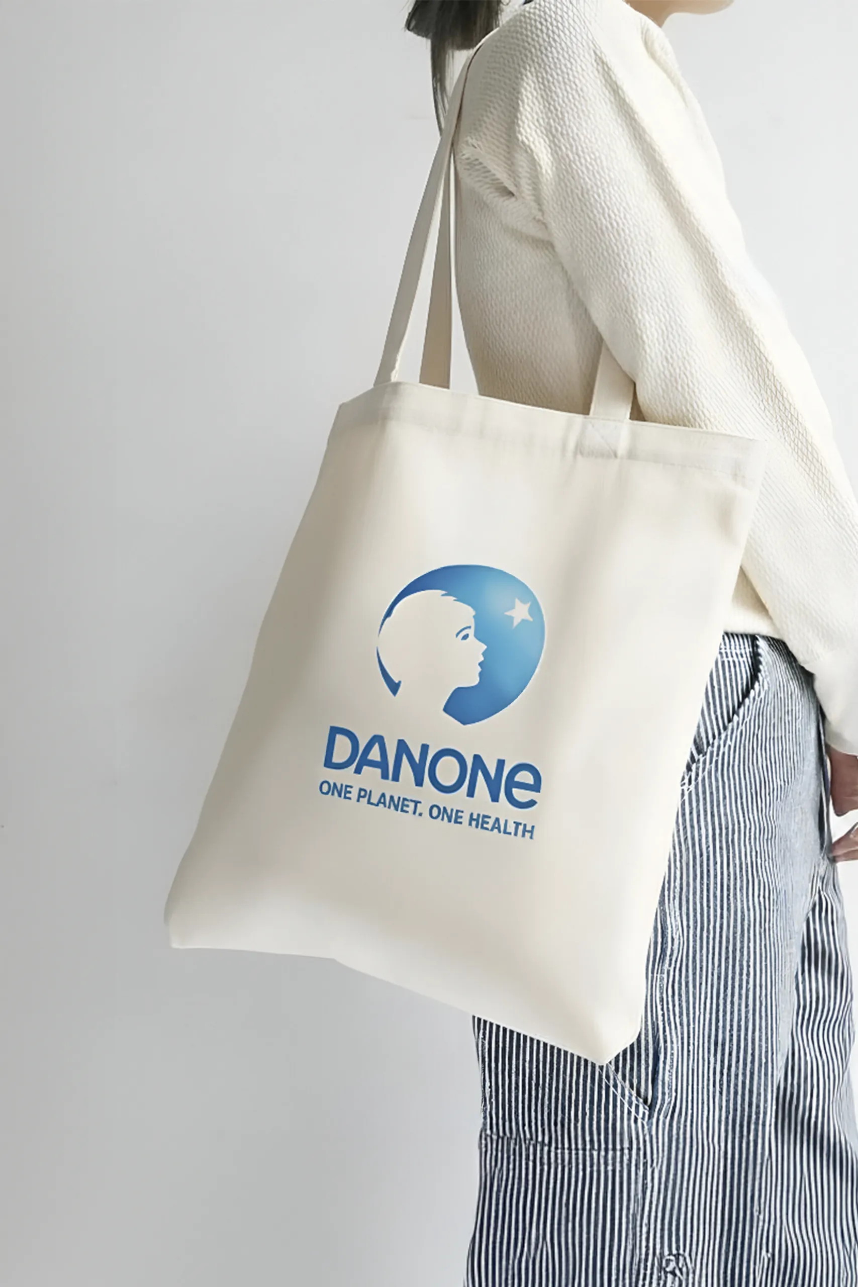Bolsa blanca de tela con diseño personalizado de Danone colgada de un hombro