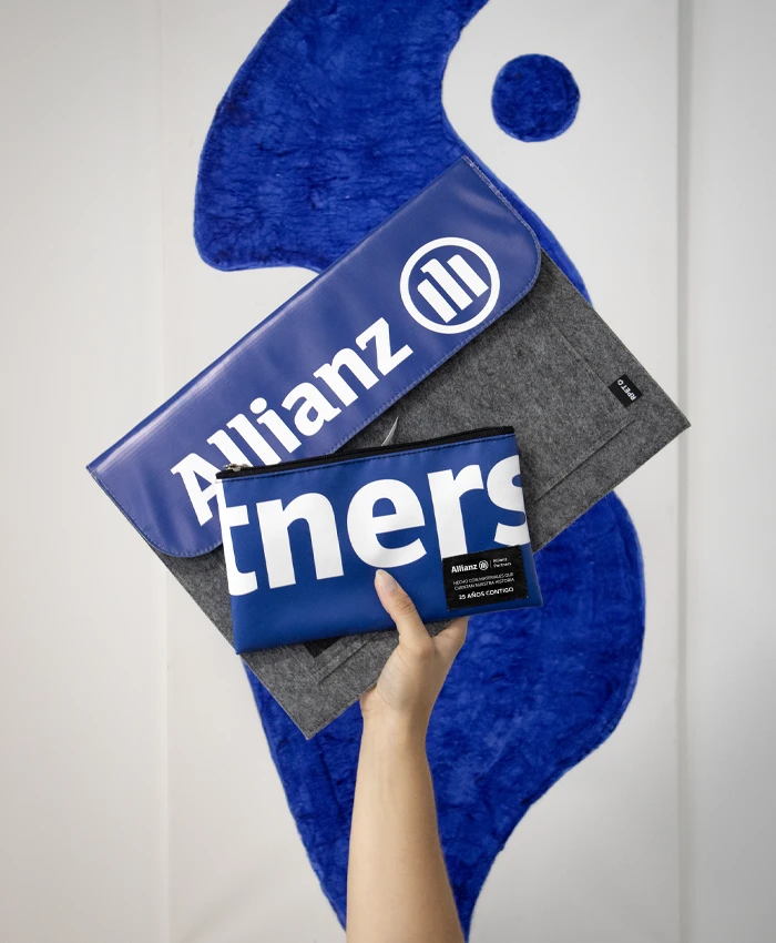 Mano mostrando una funda de ordenador y un neceser de lona personalizados con la marca de seguros Allianz