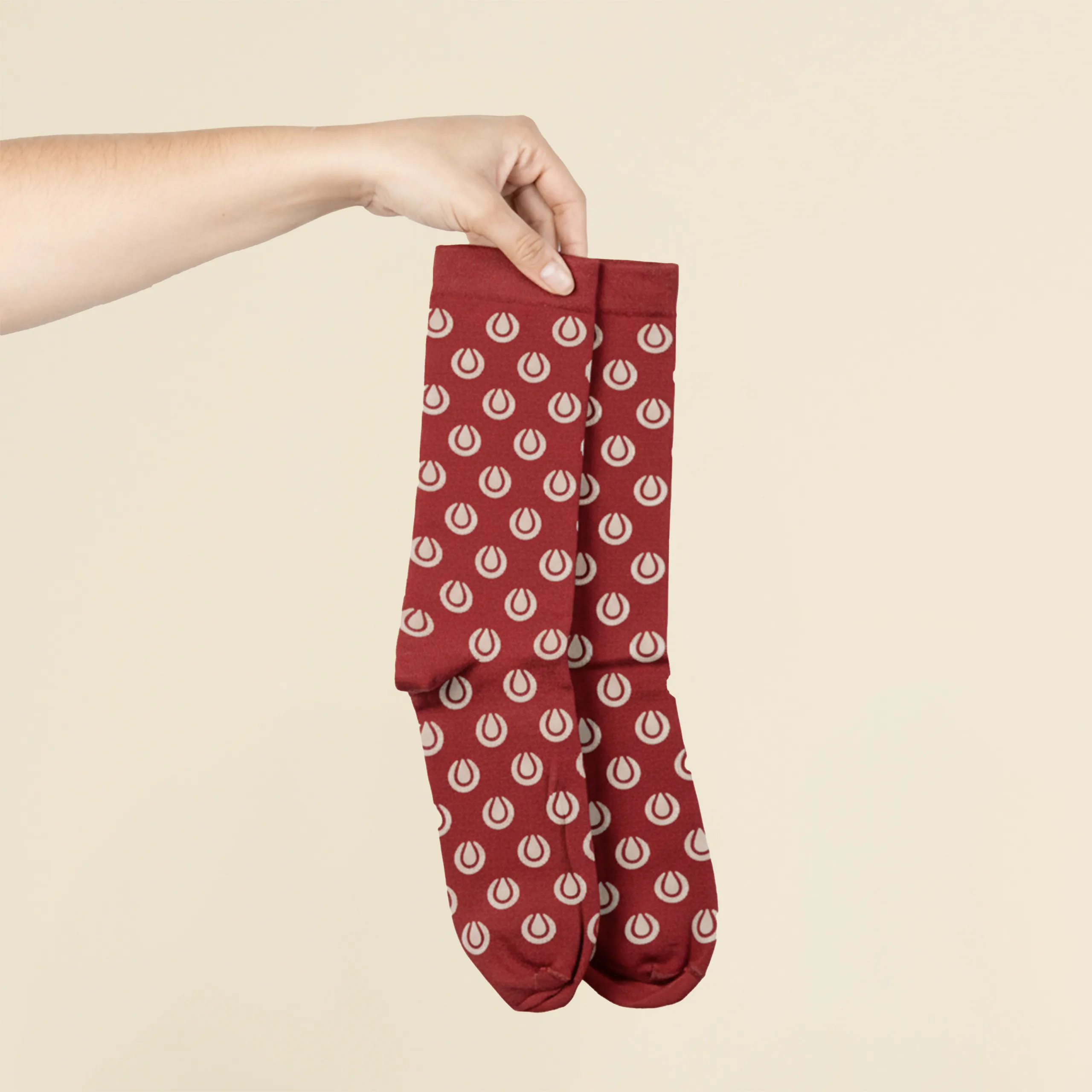 Calcetines personalizados LION Manos sosteniendo unos calcetines rojos personalizados con logo sobre un fondo beige