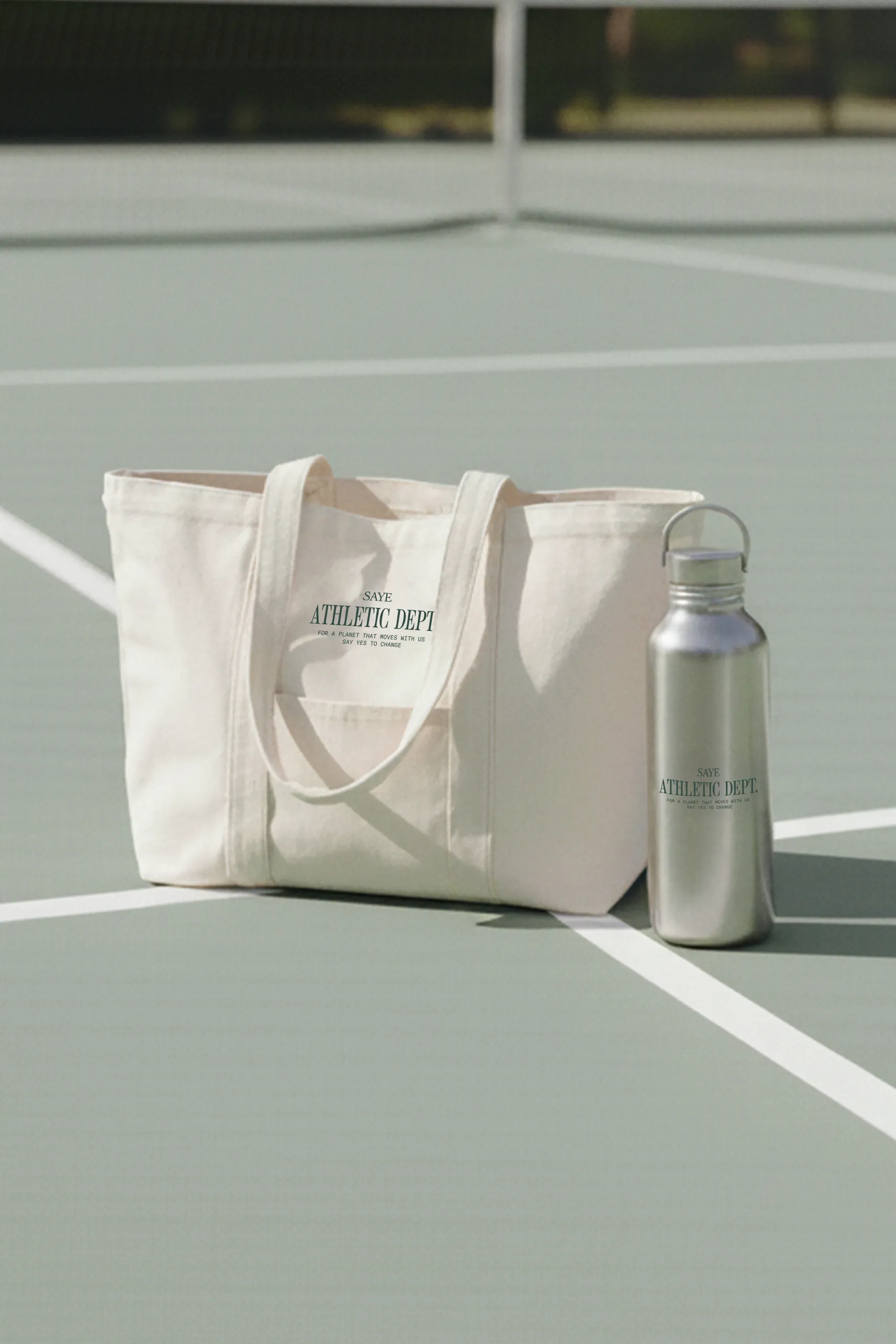 Tote bag personalizada y sostenible con una botella de aluminio sostenible y personalizado en un campo de tenis