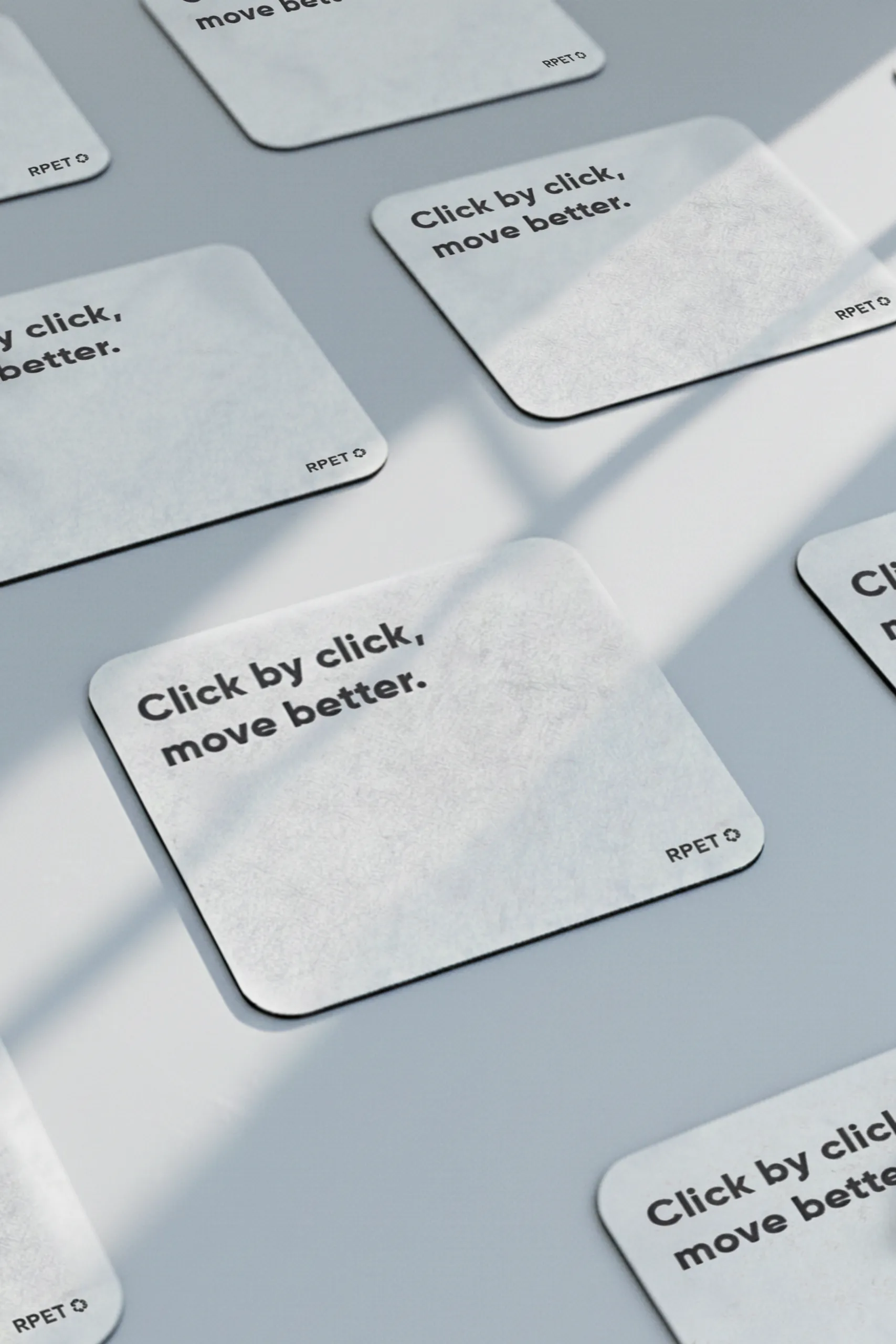 Alfombrillas de ordenador de fieltro gris personalizadas dispuestas sobre una superficie gris