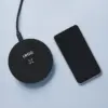 Cargador inalámbrico negro personalizado con la palabra 'LOGO' junto a un teléfono móvil iphone