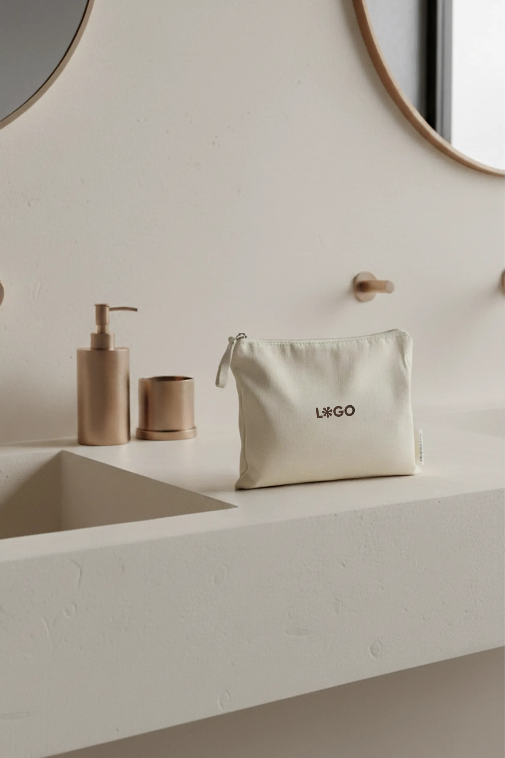 Un neceser beige de algodón personalizado con la palabra "LOGO" en marrón apoyado en la superficie de un lavabo de un baño