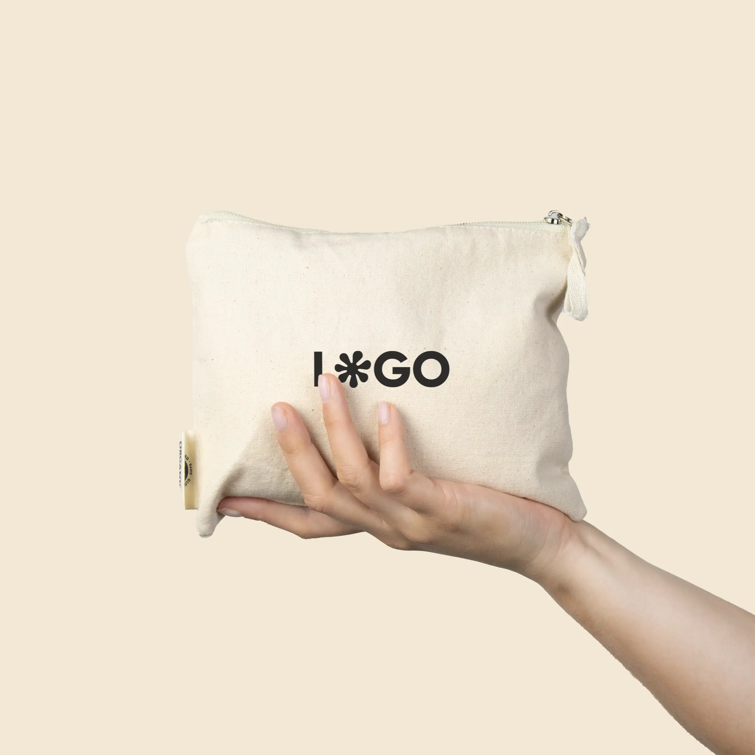 Mano sujetando un neceser beige de algodón personalizado con la palabra "LOGO" en negro