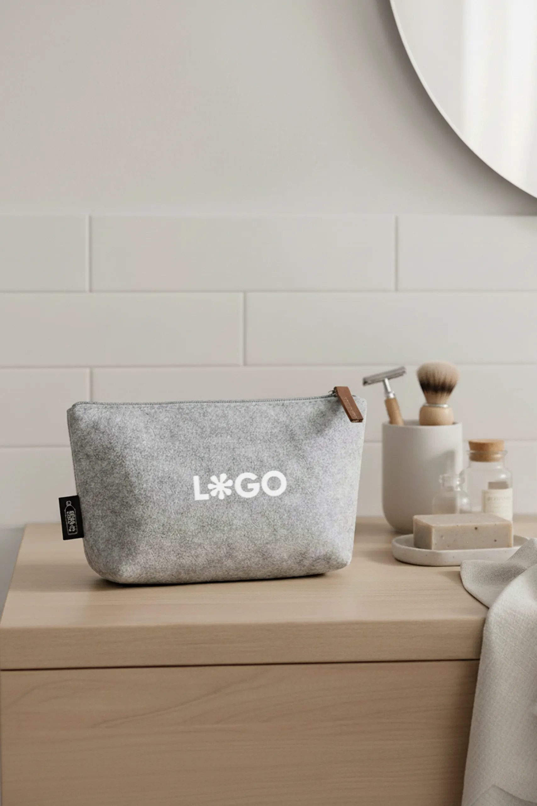 Neceser de viaje de color gris personalizado con la palabra logo en blanco sobre una superficie de madera dentro de un baño