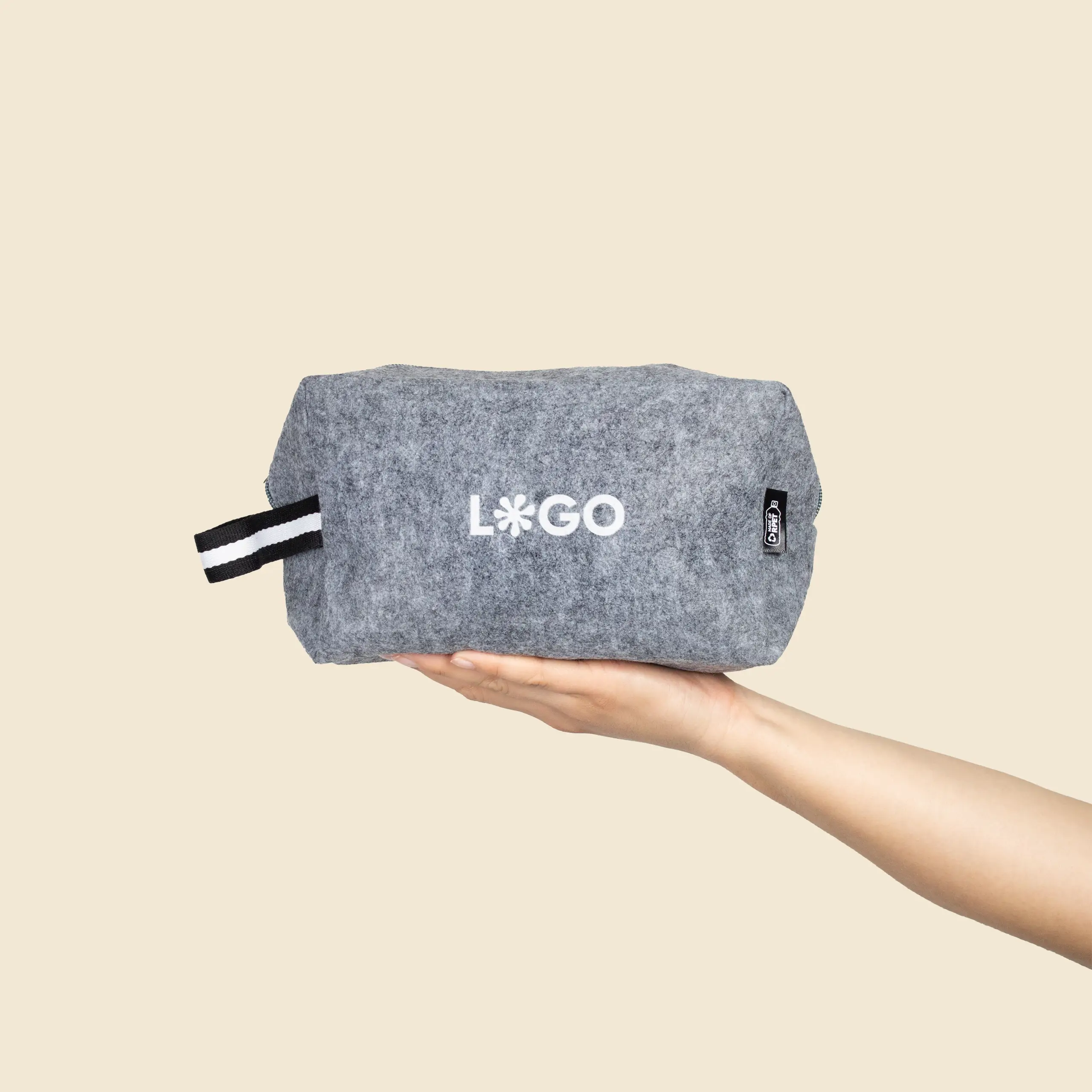 Neceser fieltro con asa FELT Mano sosteniendo un neceser de fieltro con asa personalizado con la palabra 'logo' en blanco