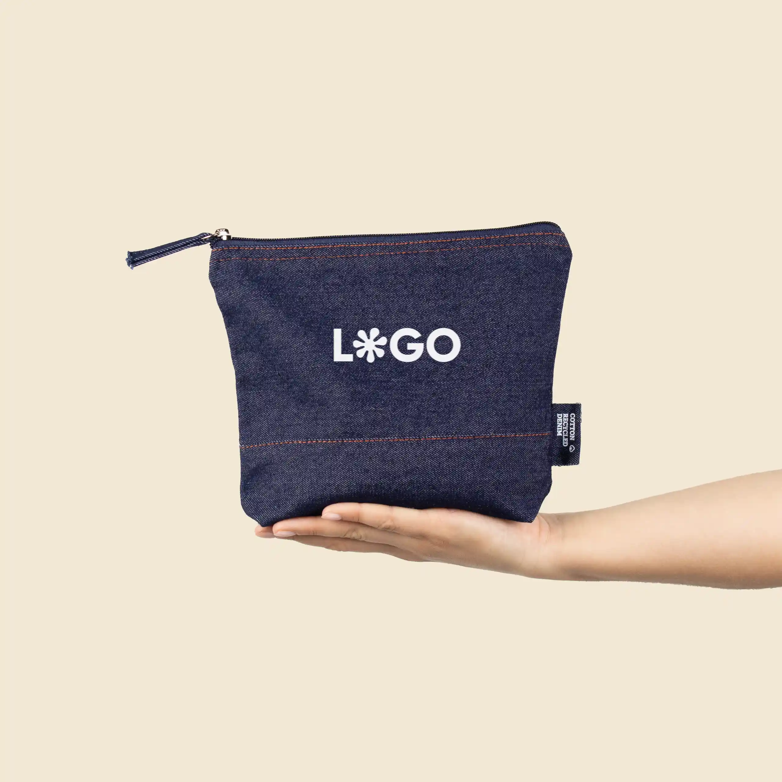 Trousse de toilette en jean 'NUDO' Mano sosteniendo un neceser de vaquero personalizado con la palabra 'logo' en blanco
