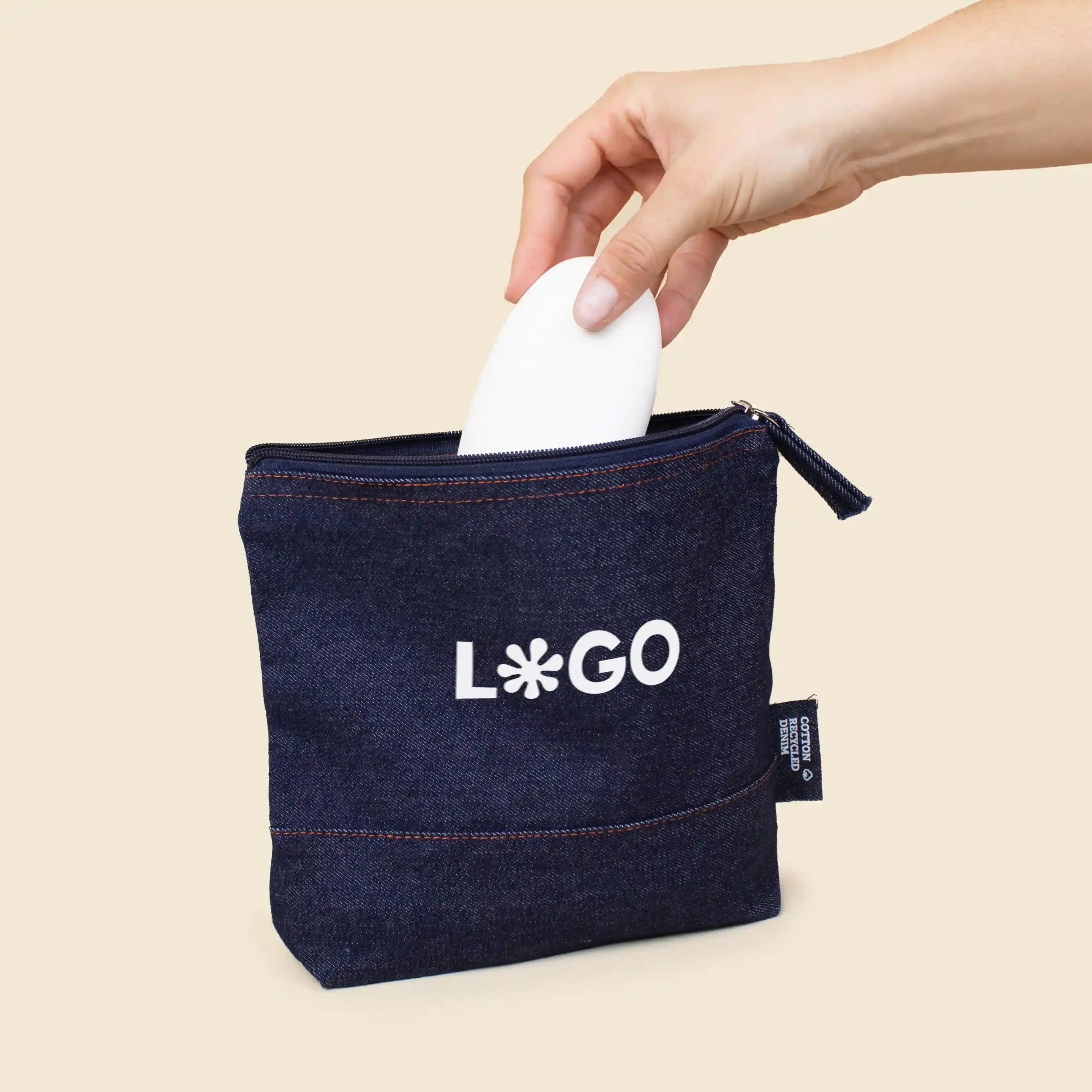 Neceser vaquero personalizado NUDO Mano sacando un producto de un neceser de vaquero personalizado con la palabra 'logo' en blanco