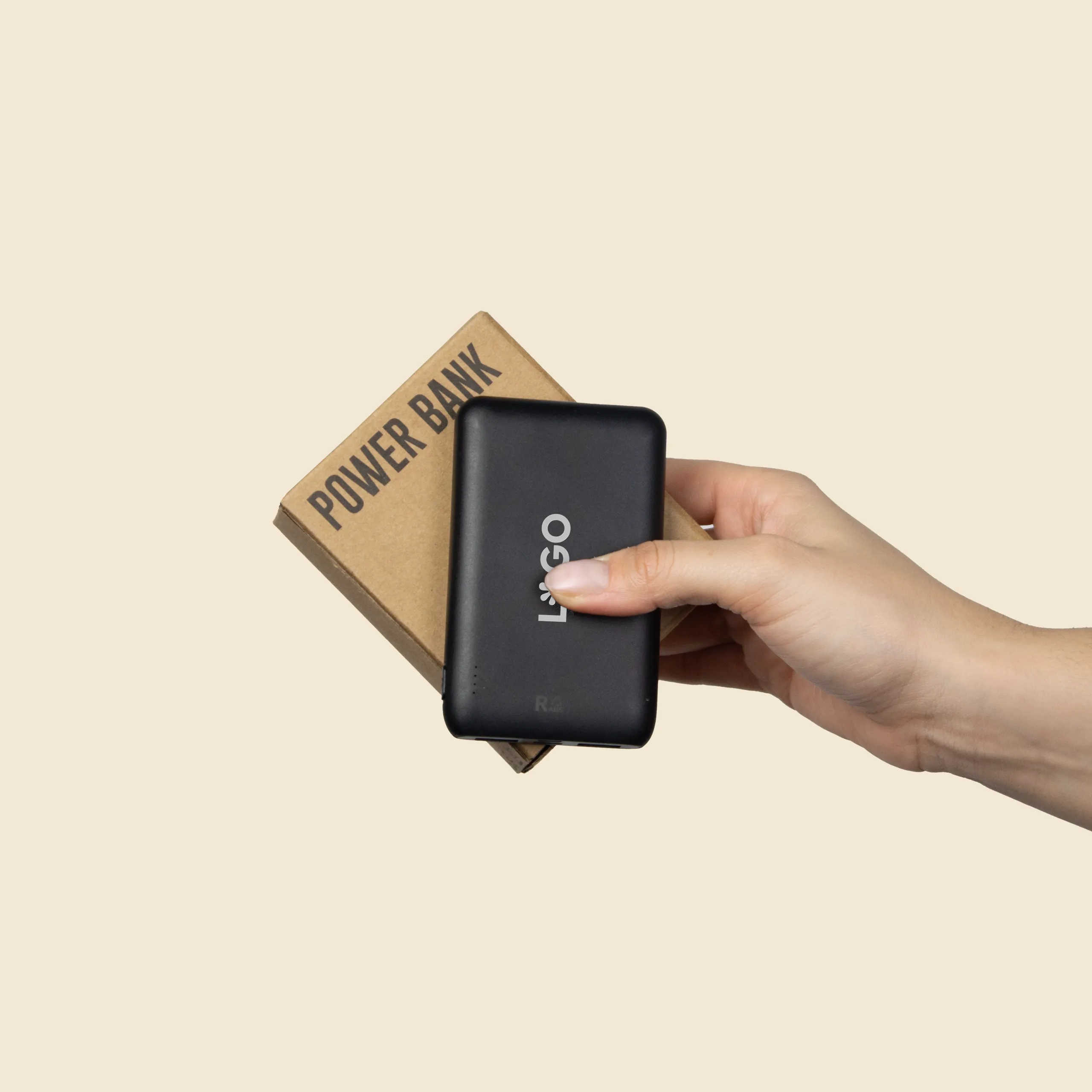 Batería externa personalizada REVOLT Mano sujetando una batería externa de color negro junto a su caja de cartón