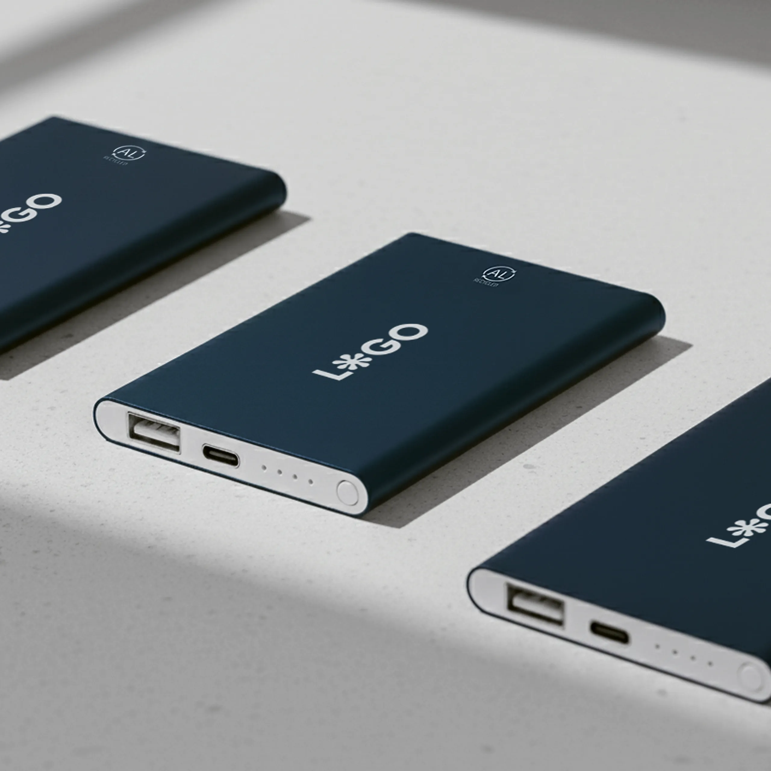 Tres baterías portátiles de color azul marino personalizadas con la palabra "LOGO" en blanco