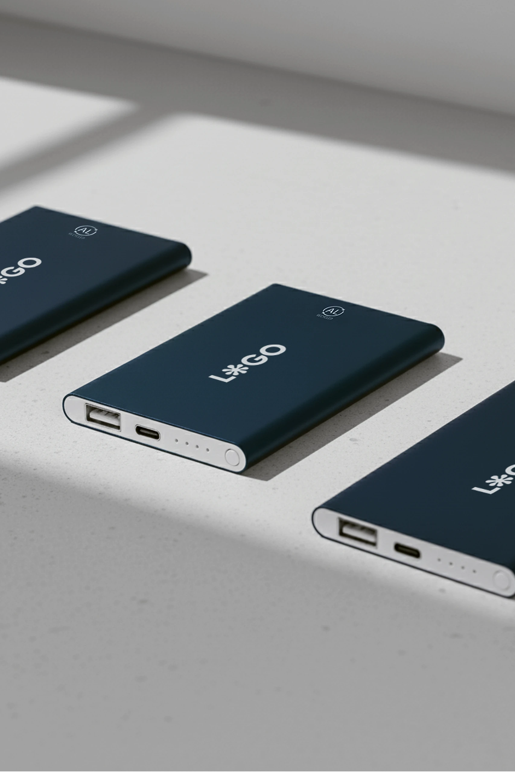 Tres baterías portátiles de color azul marino personalizadas con la palabra "LOGO" en blanco