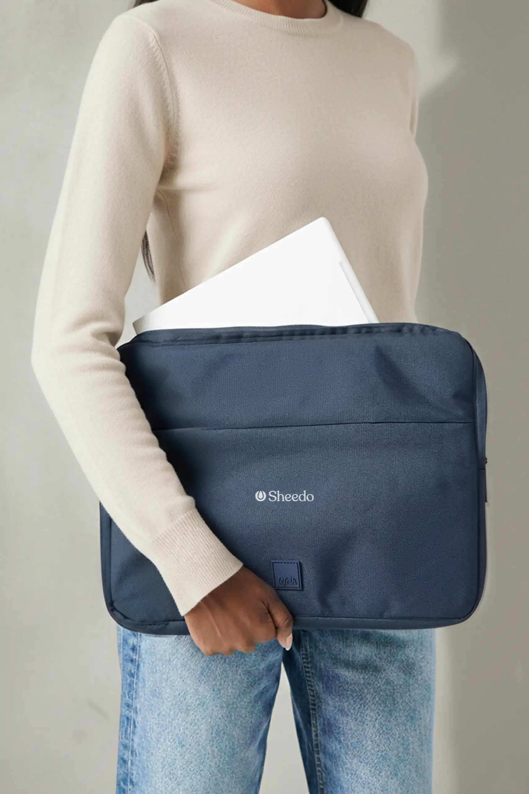 Chica llevando una funda de portátil azul de la marca Lefrik personalizada con el texto "YOUR LOGO" en blanco