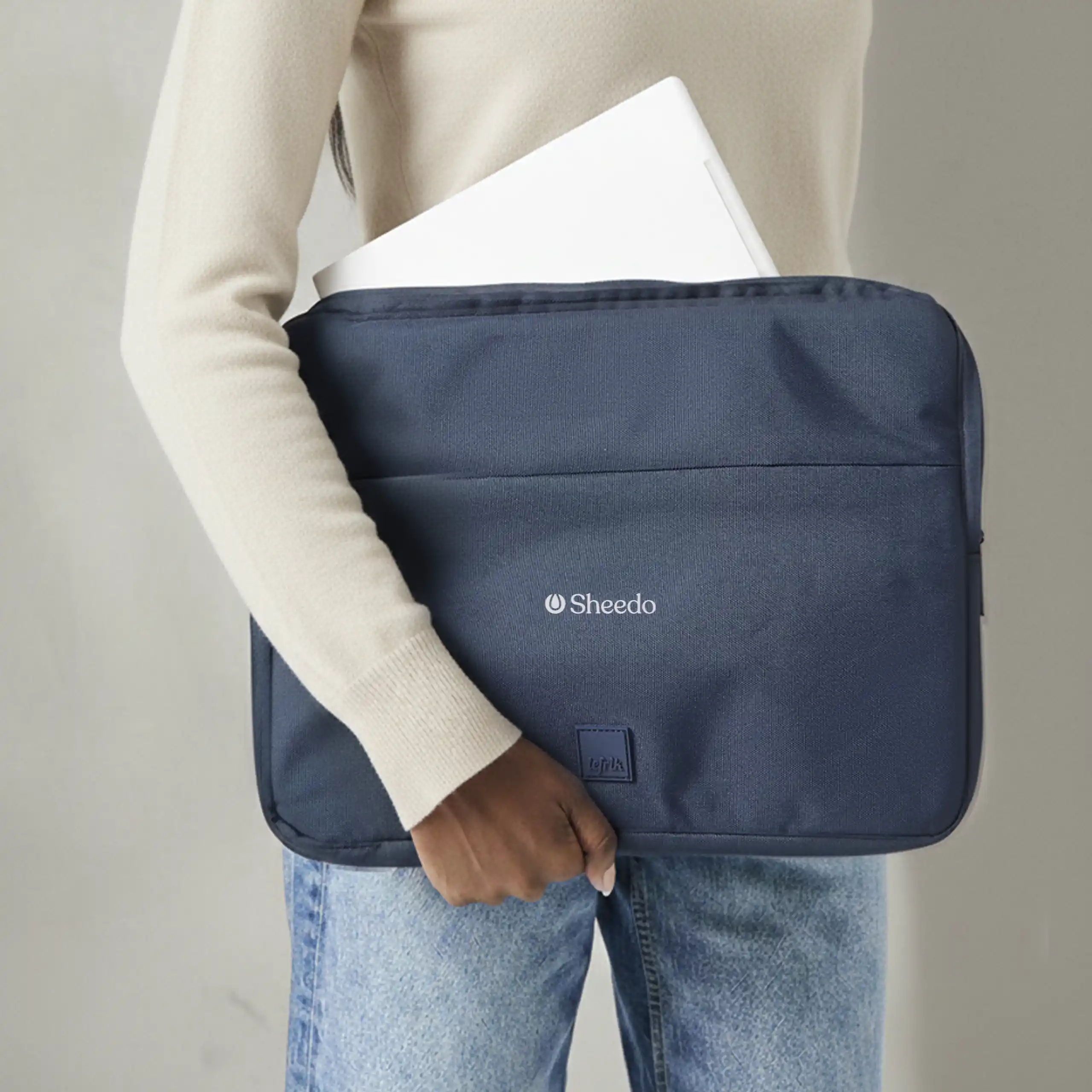 Funda de portátil LEFRIK CAPTURE 13 Chica llevando una funda de portátil azul de la marca Lefrik personalizada con el texto "YOUR LOGO" en blanco