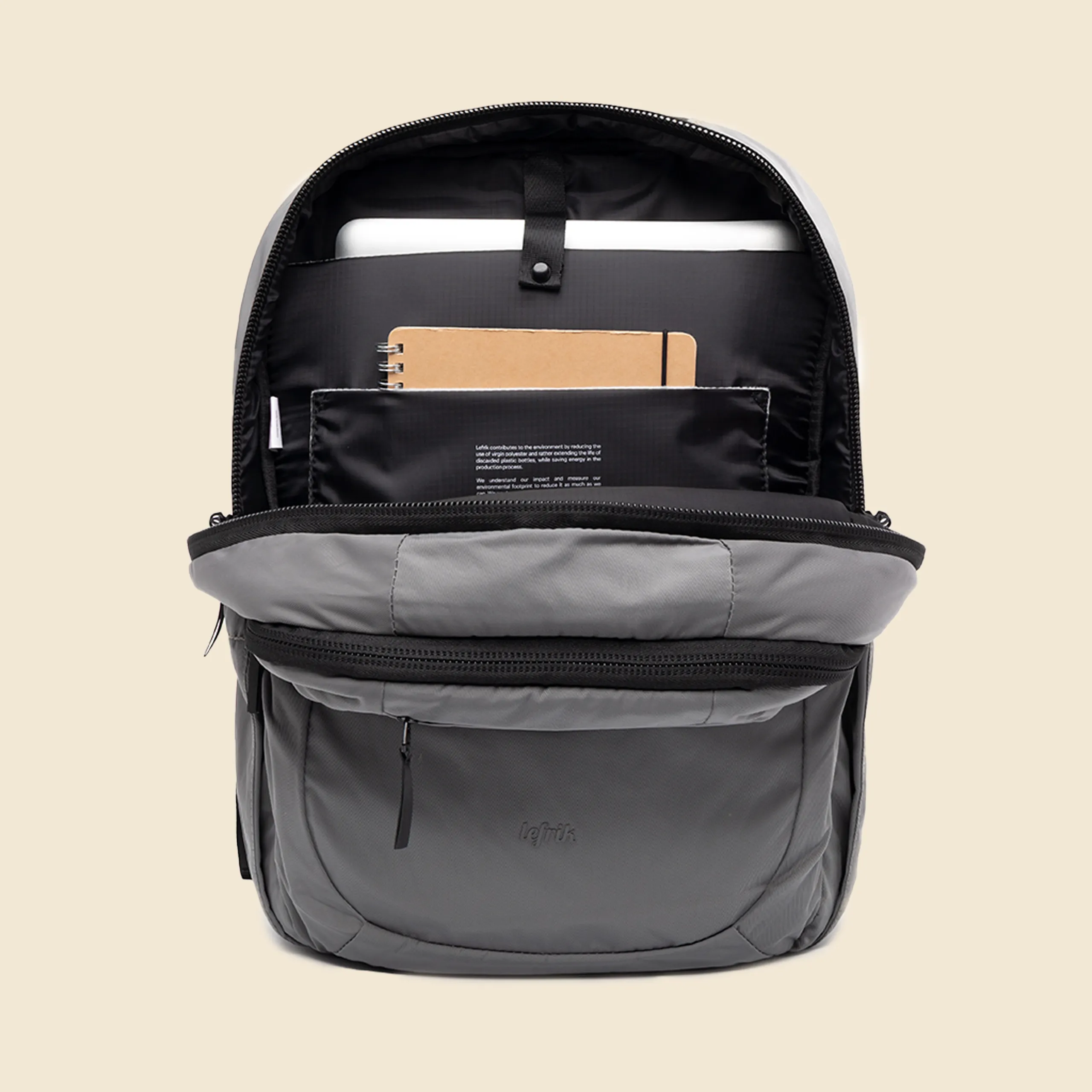 Mochila gris de la marca Lefrik abierta con un cuaderno y un portátil en su interior