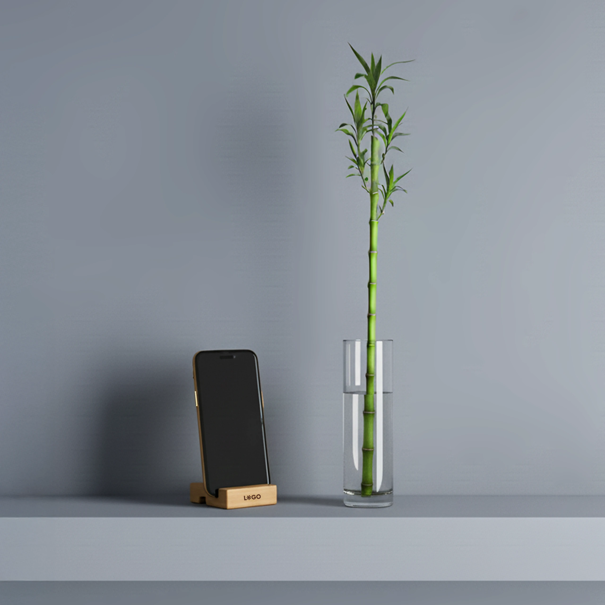 Soporte para móvil personalizado con la palabra "LOGO" impresa en marrón con un iphone, junto a un jarrón de cristal con agua y una rama de bambú