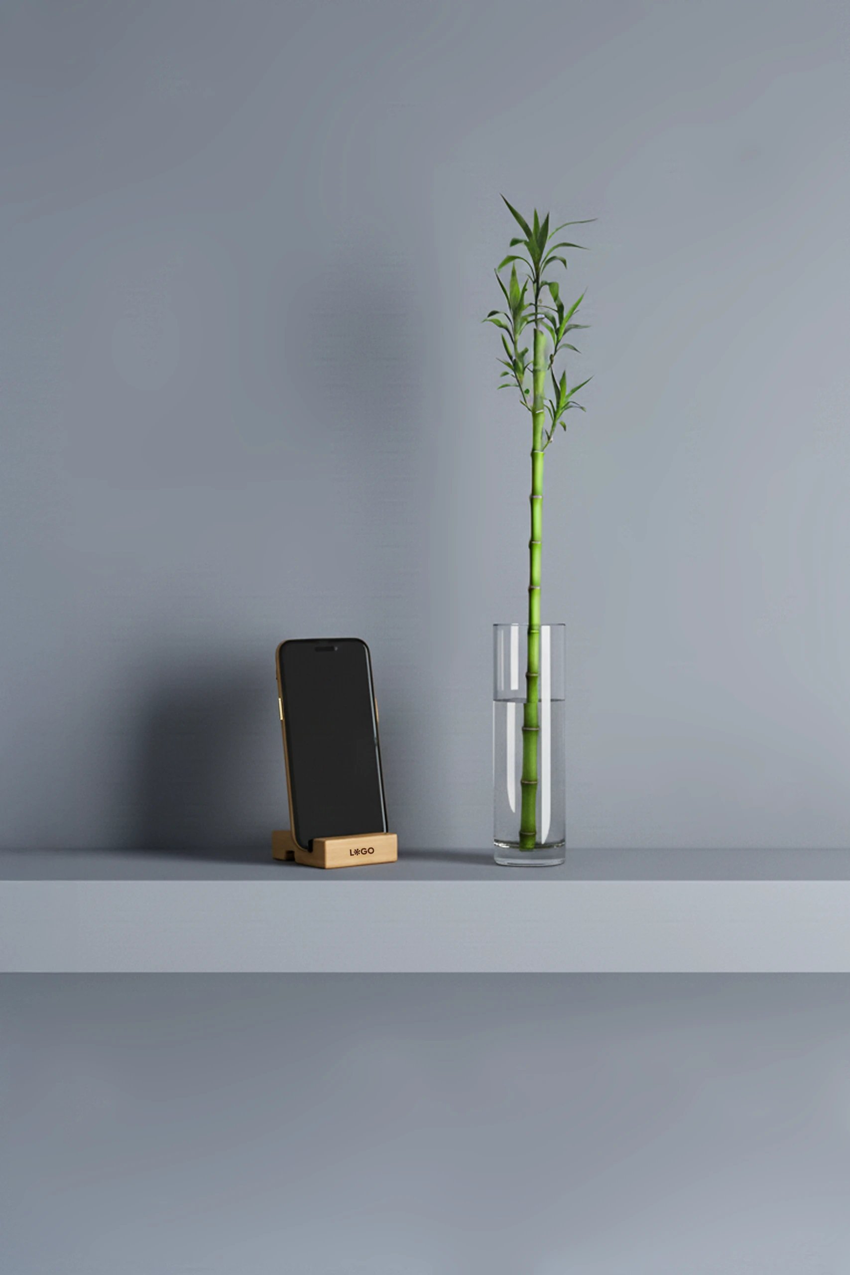 Soporte para móvil personalizado con la palabra "LOGO" impresa en marrón con un iphone, junto a un jarrón de cristal con agua y una rama de bambú