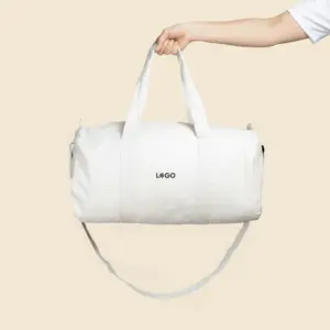 Bolsa de gimnasio personalizada sujeta por un brazo con camiseta blanca de algodón. De algodón reciclado y color beige. Con personalización a todo color marrón.