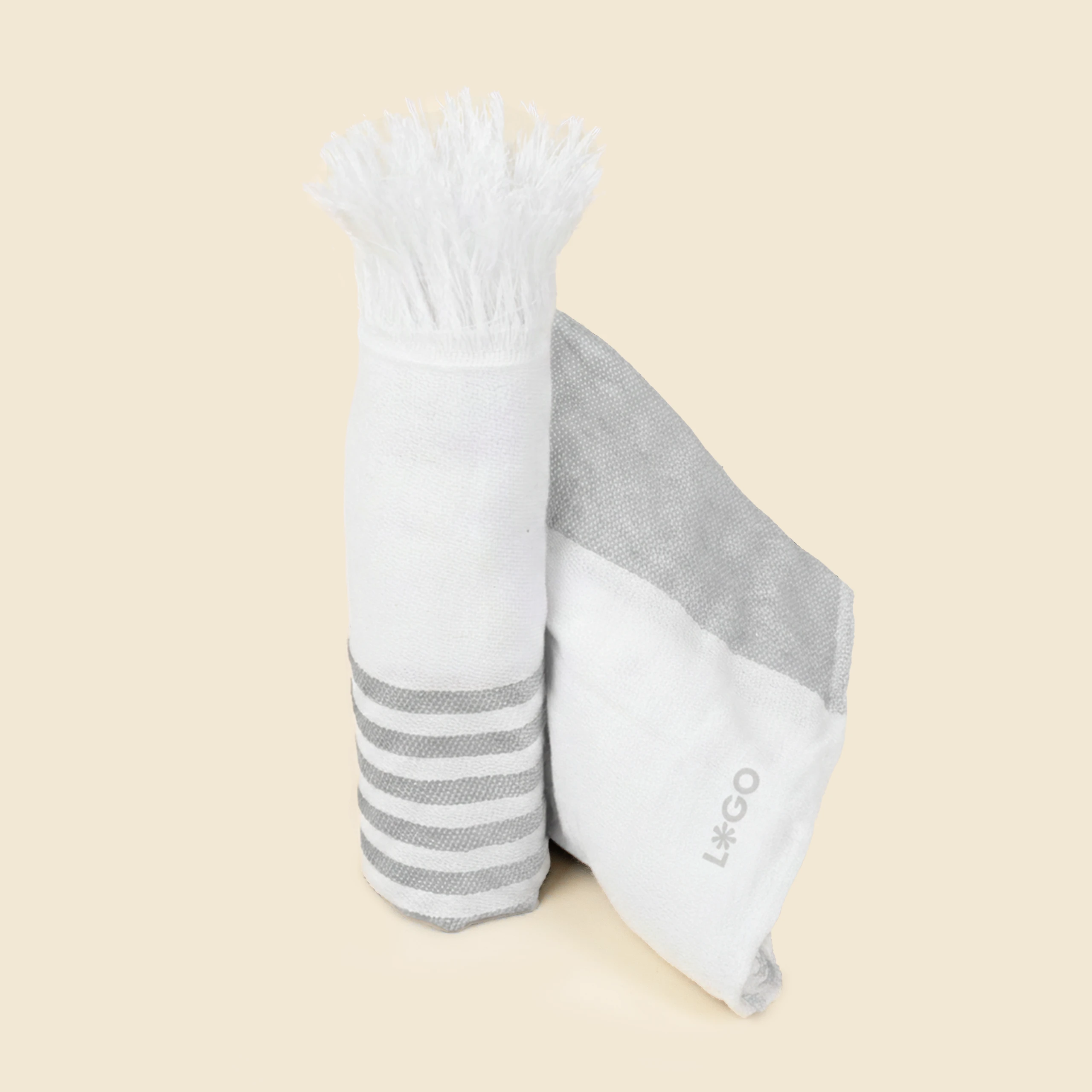 Drap de plage personnalisé _MARINA Toalla pareo enrollado y personalizado. Con flecos y de color gris y blanco a rayas.