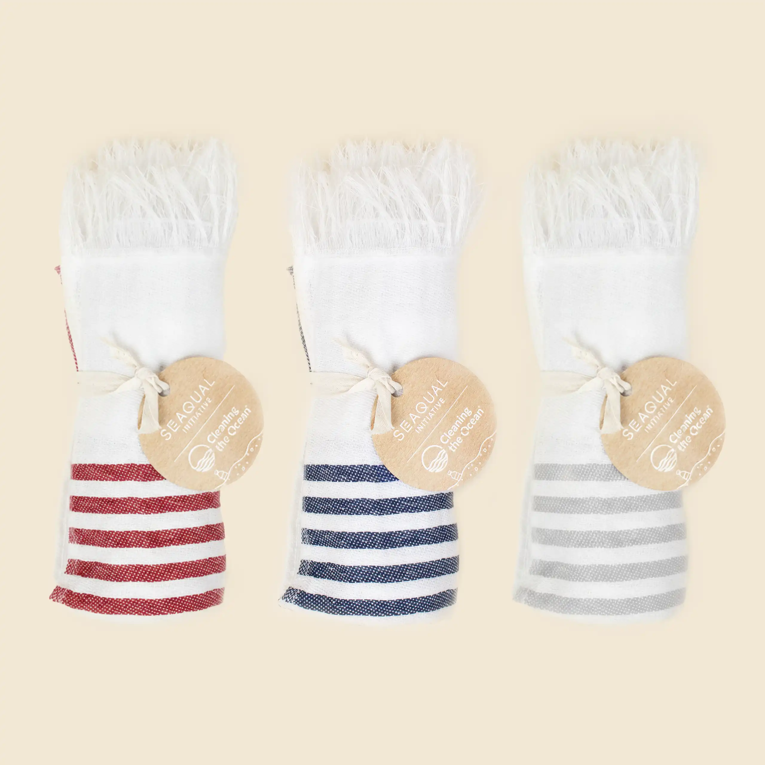 Toalla pareo personalizado. Con flecos y de color azul, rojo y gris con blanco a rayas. Con etiqueta SEAGUAL.