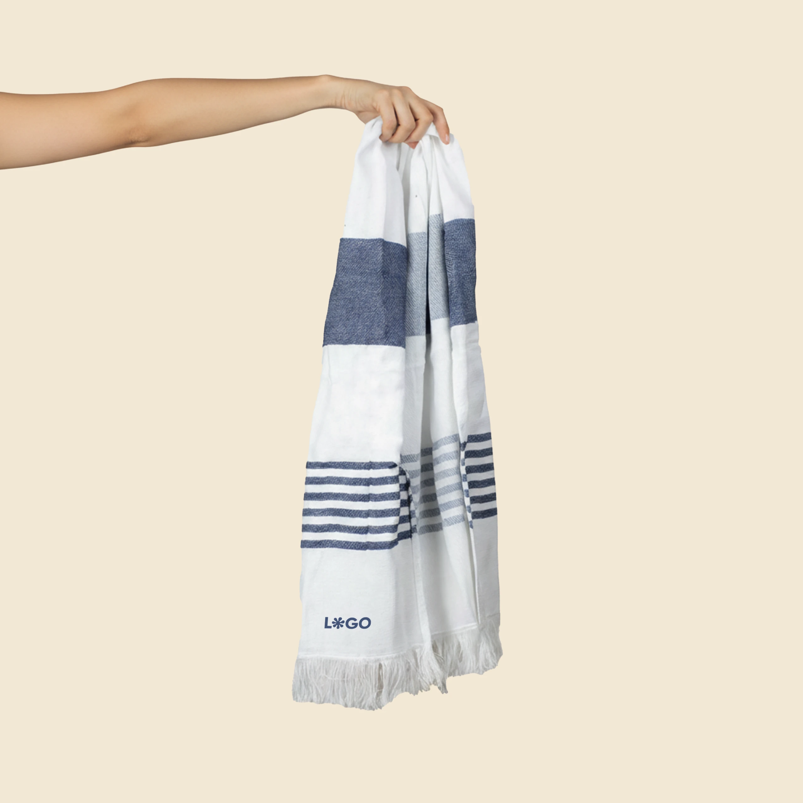 Toalla pareo personalizado. Con flecos y de color azul y blanco a rayas. Sujeto con una mano.