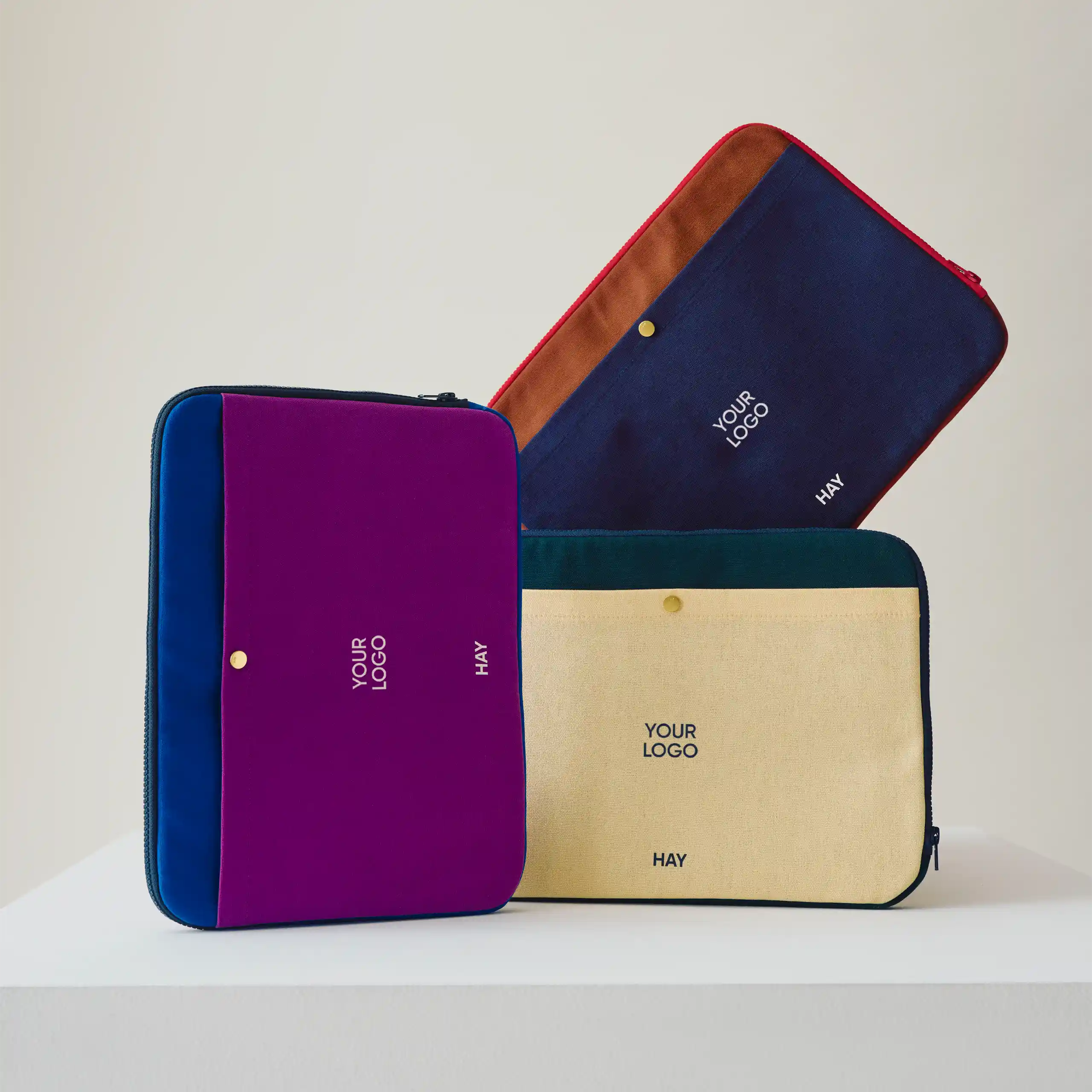 Funda de portátil de la marca HAY. Con botón dorado y cremallera. Combinado de colores.