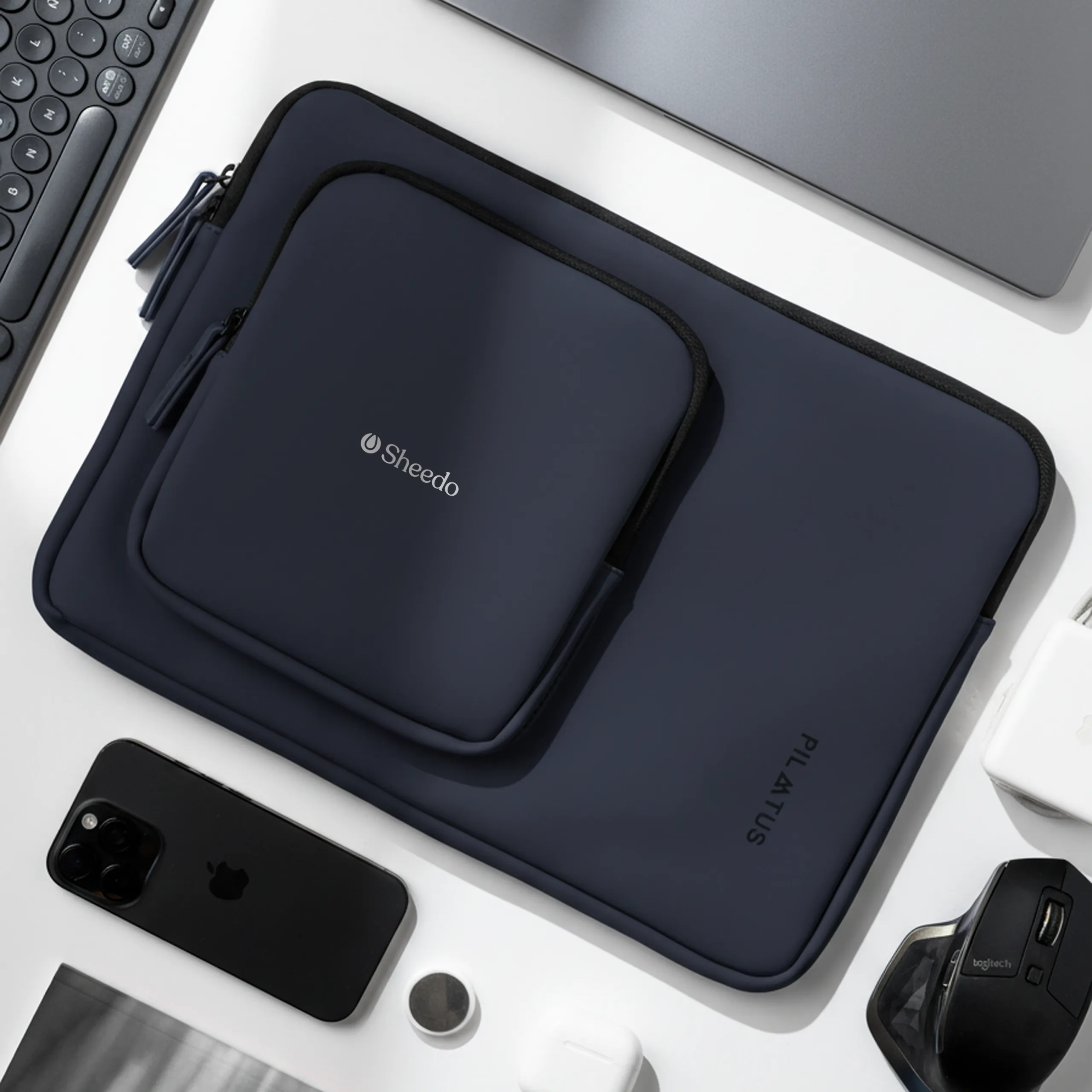 Funda de portátil - Pilatus Sleeve 16 Funda de portátil - Pilatus Sleeve de 16'' pulgadas. De color azul y con personalización a una tinta. Colocada en una mesa de oficina.