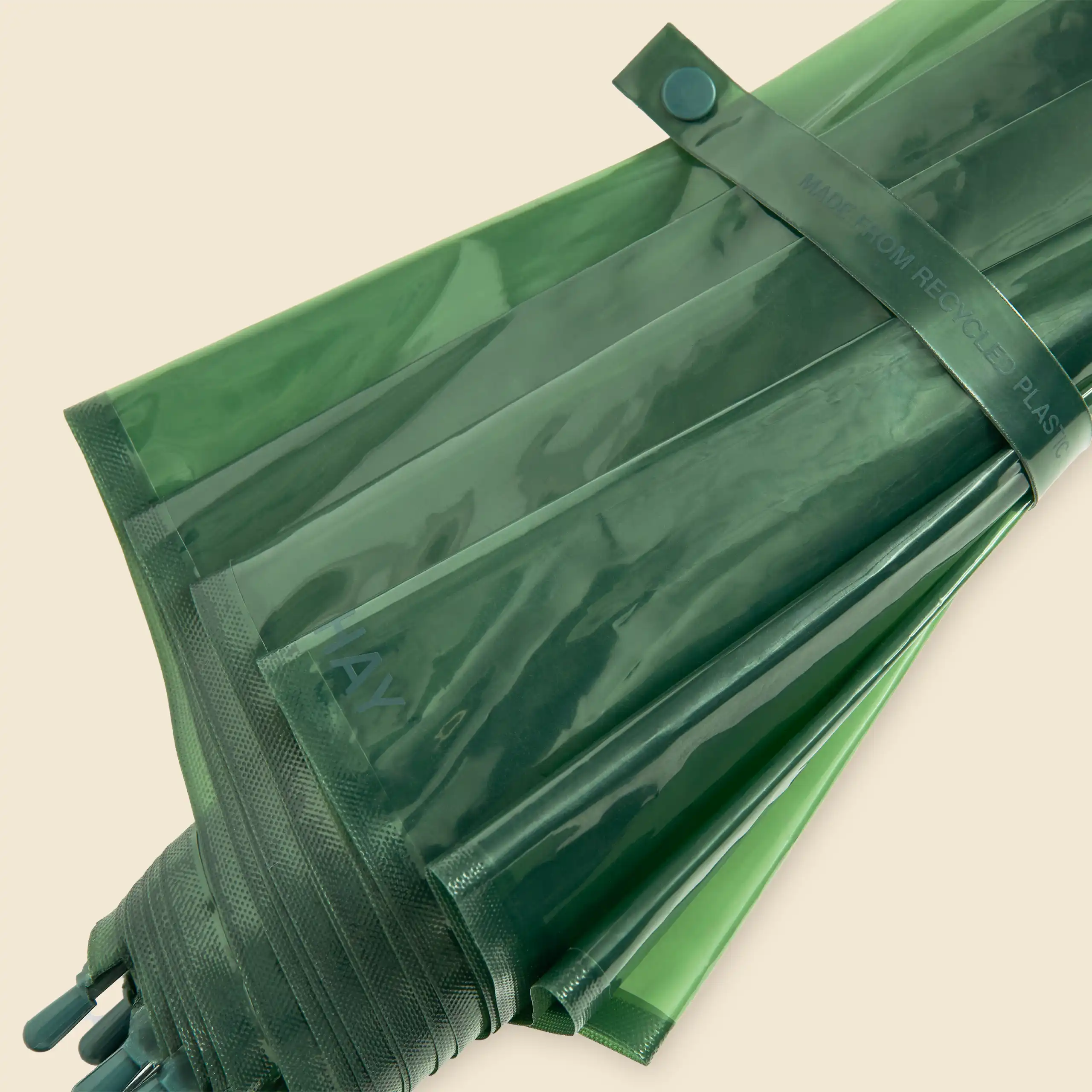 Paraguas de diseño verde transparente de la marca HAY. Con varillas de fibra de vidrio y mango curvado. Plegado con sujeción de botón.