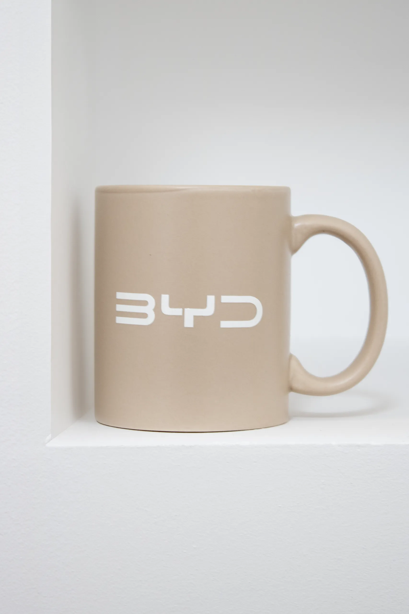 Taza de color beige personalizada con el logotipo de la marca BYD en color blanco