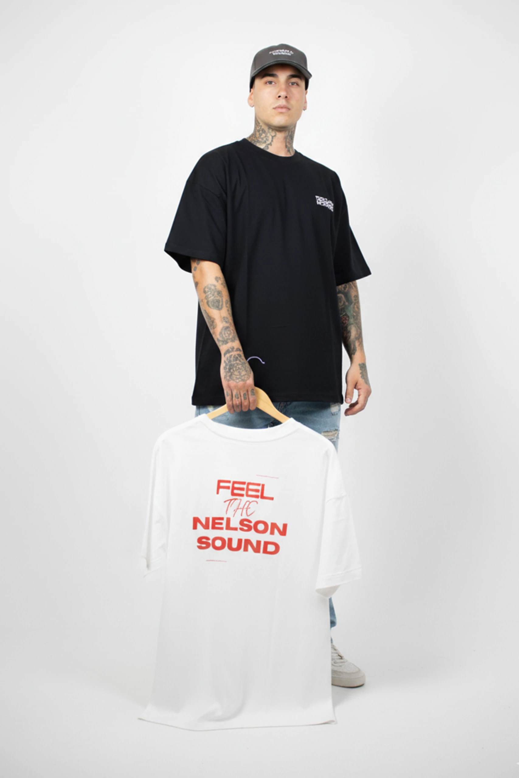 Chico sujetando una percha de madera con una camiseta oversize blanca personalizada para la marca personal DJ Nelson
