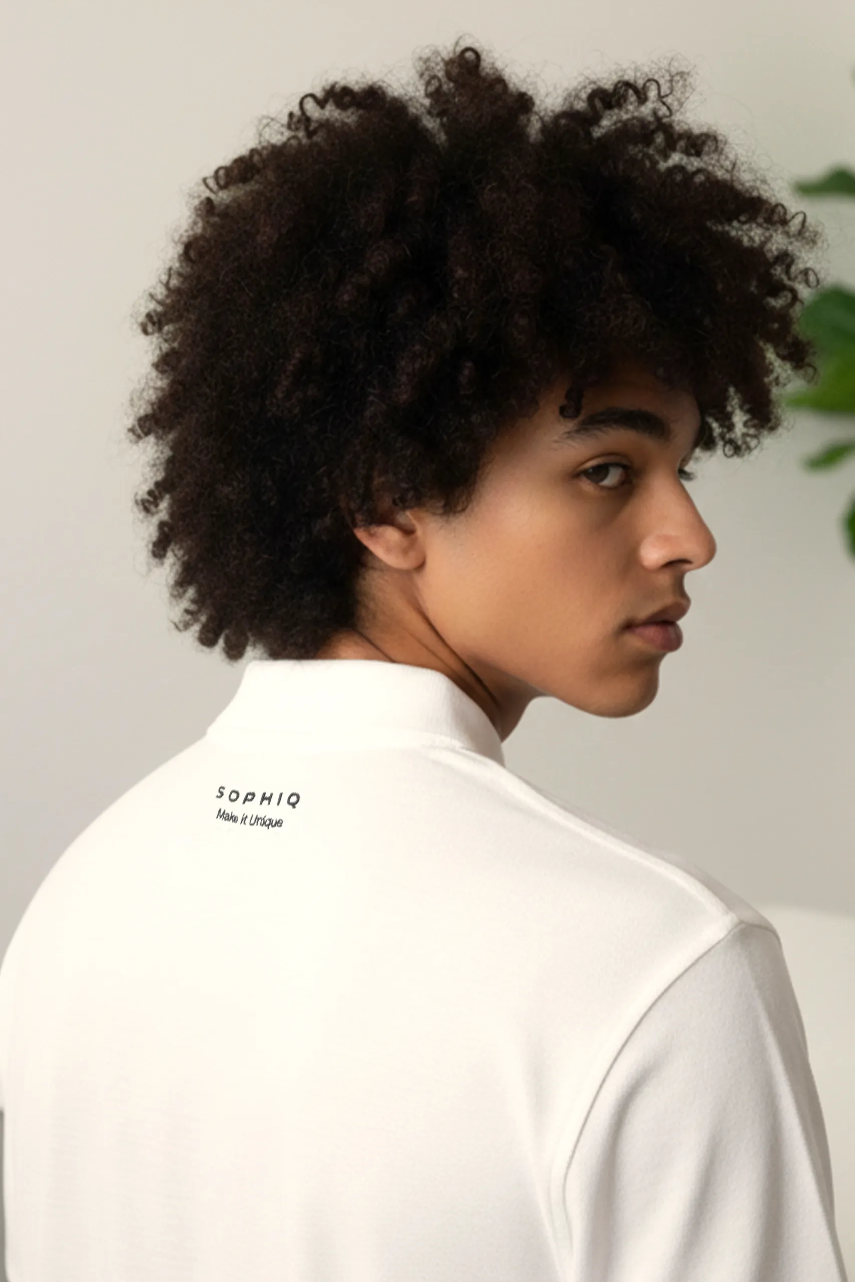 Chico de espaldas con un polo blanco personalizado con el logo de la marca Sophiq Properties
