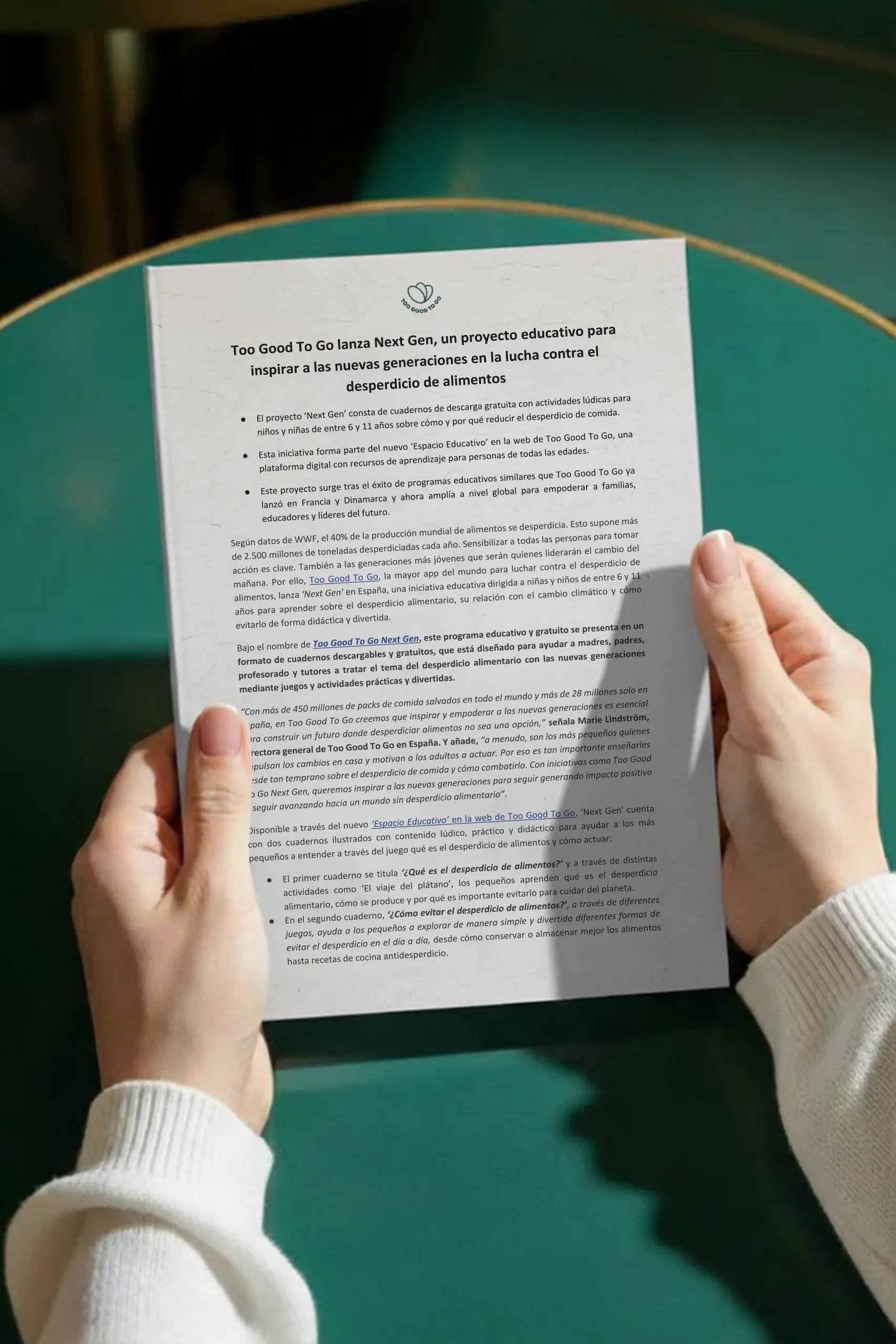 Dos manos sujetando una hoja A4 impresa para la marca Too Good To Go