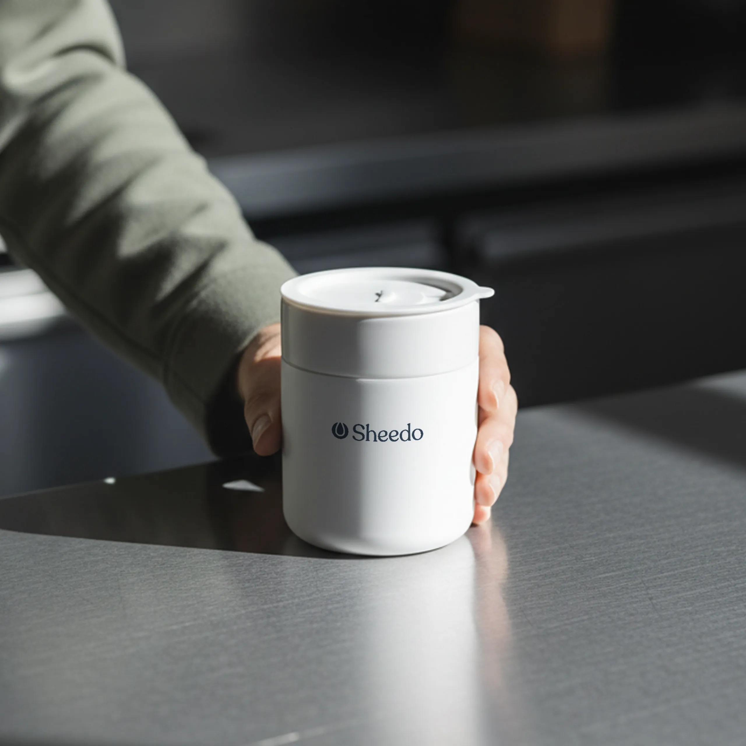 Vaso de cerámica ARCHI Mano sujetando un vaso de cerámica blanco personalizado con el logotipo de Sheedo
