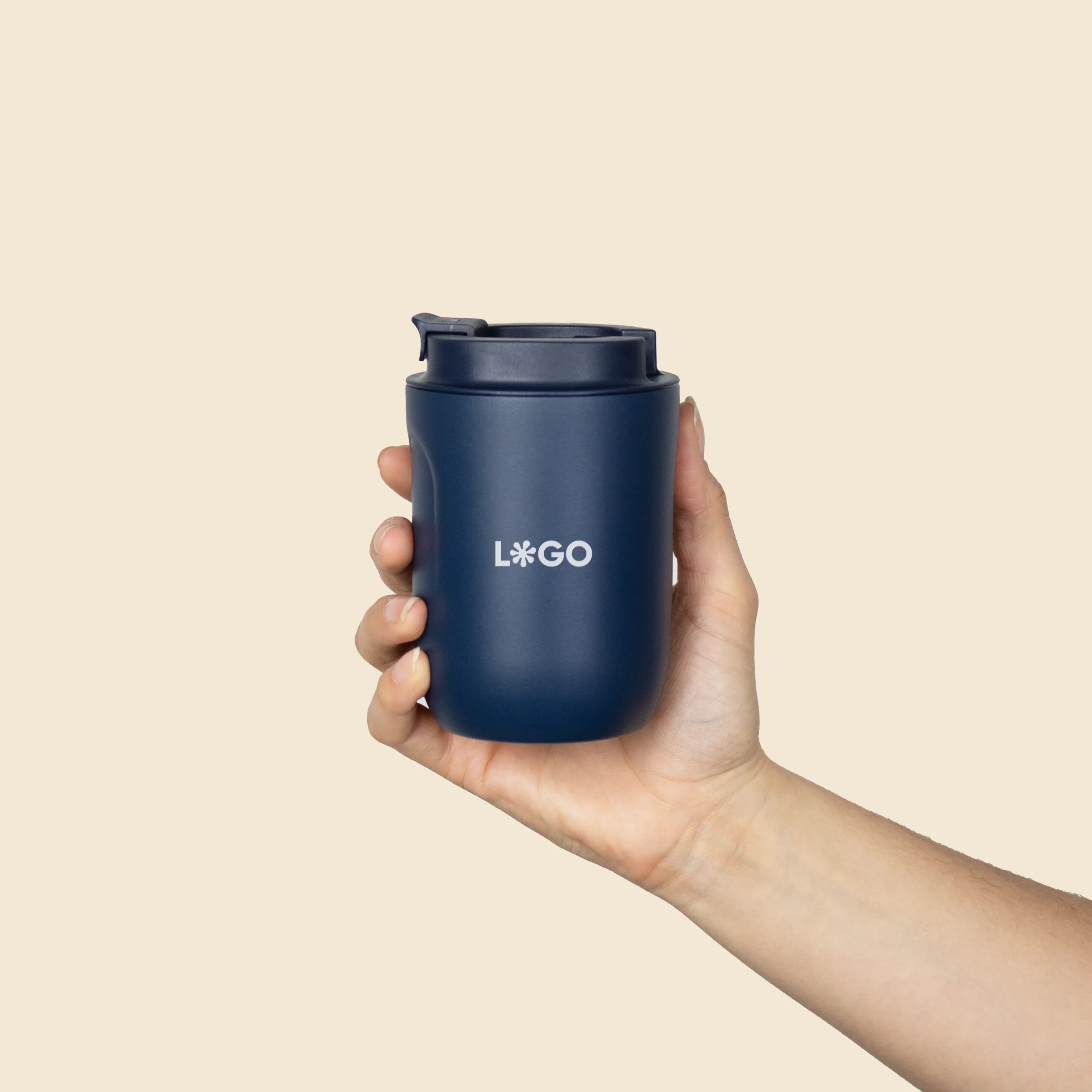 Mano sujetando un vaso térmico azul personalizado con la palabra 'logo' en blanco