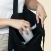 Chica abriendo una bolsa negra de algodón reciclado y metiendo un termo en ella.