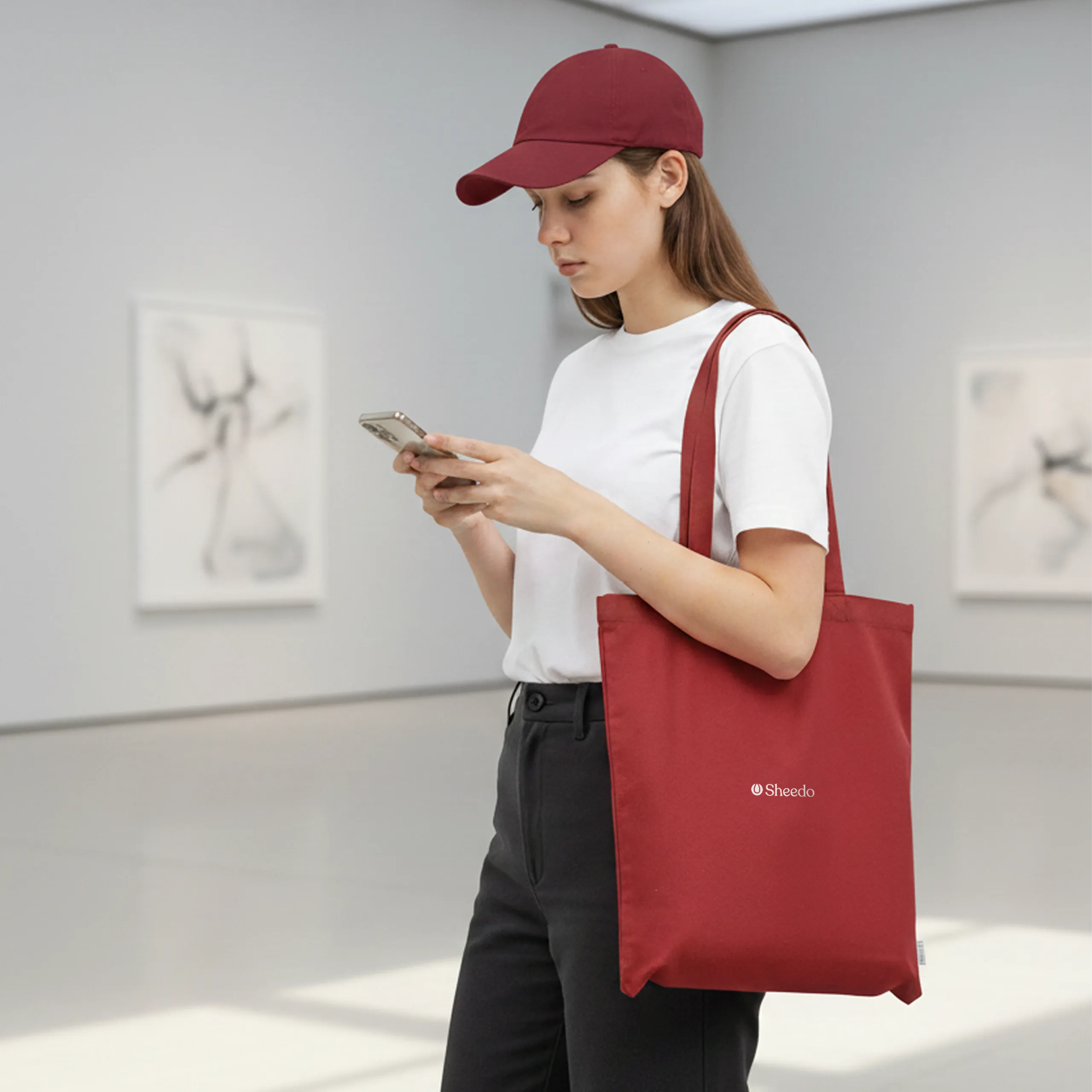 Chica en un museo con una bolsa de algodón reciclado de color rojo con la palabra LOGO en blanco.