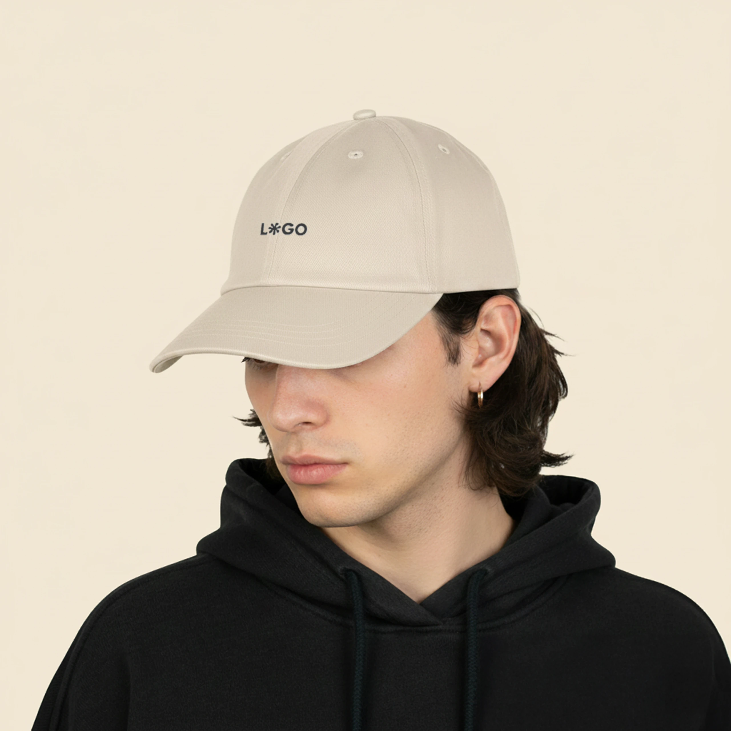 chico con sudadera negra y una gorra ecológica de algodón de color beige, personalizada con la palabra 'logo' en marrón.