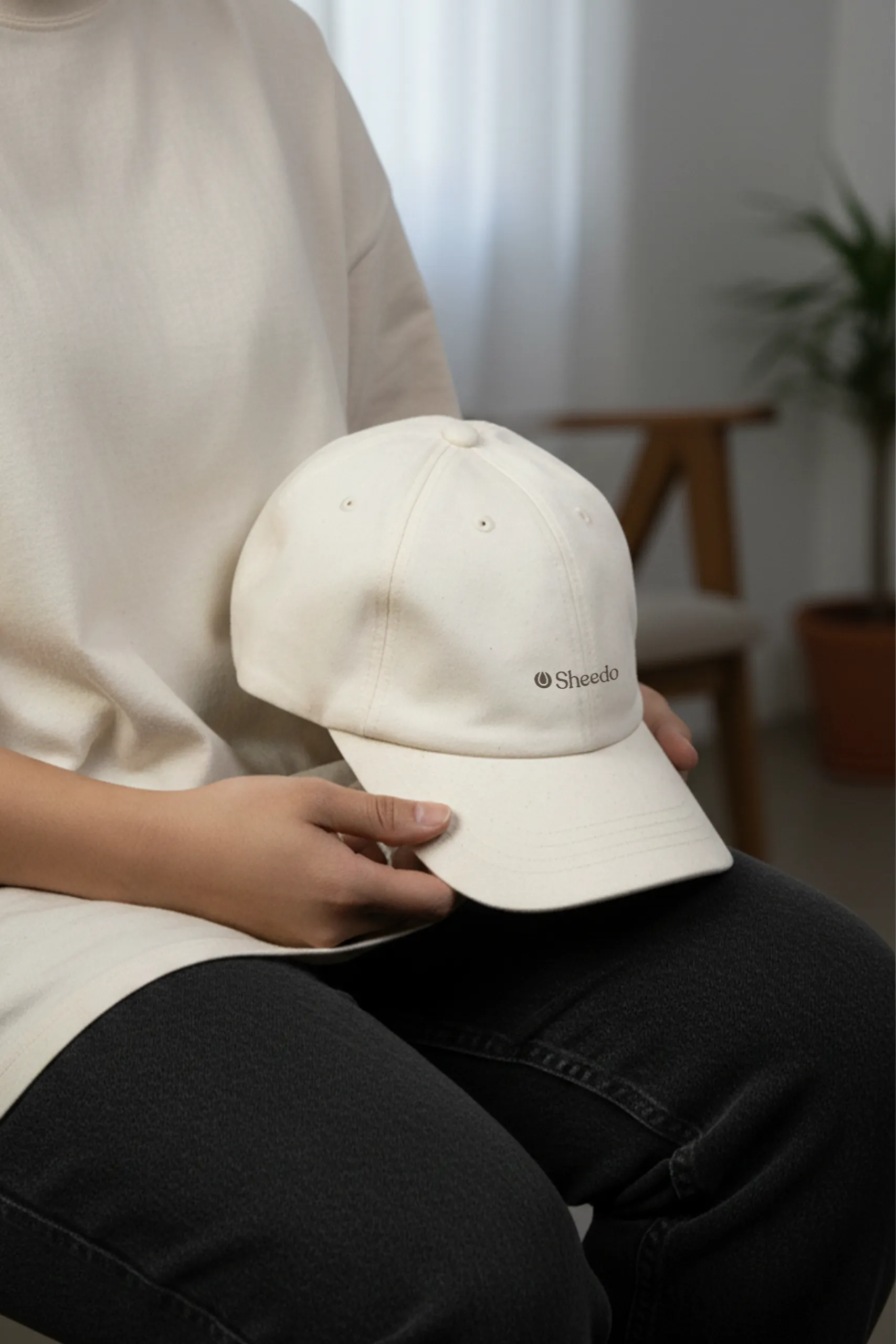 Gorra ecológica algodón orgánico GORKA Chico sujetando con sus manos una gorra ecológica de algodón de color beige personalizada con la palabra 'logo' en marrón