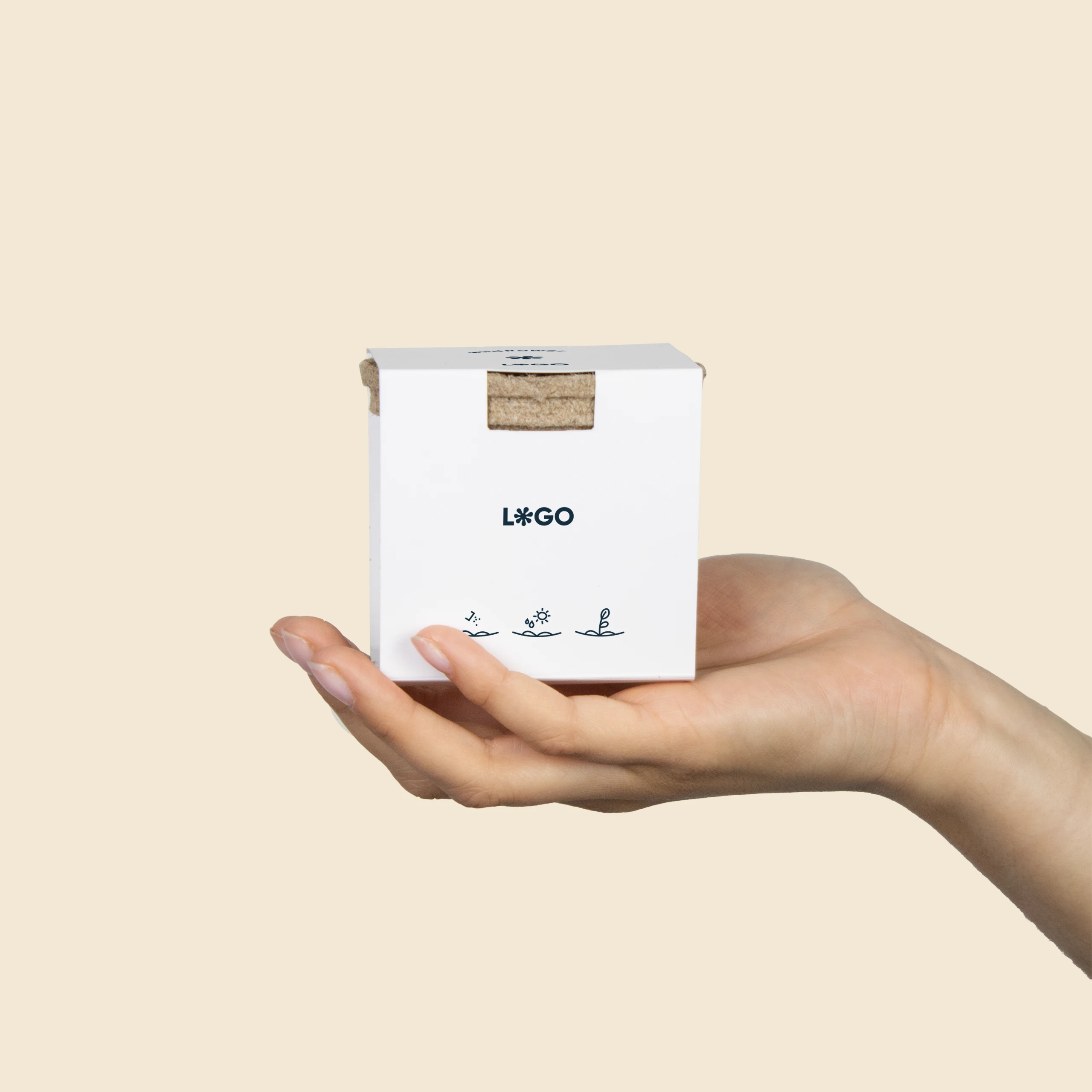 Mano sujetando un kit plantable de fibra de coco con una faja de cartón blanco personalizada