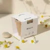 Kit plantable de fibra de coco con una faja de cartón blanco personalizada junto a una piedra y flores de margarita