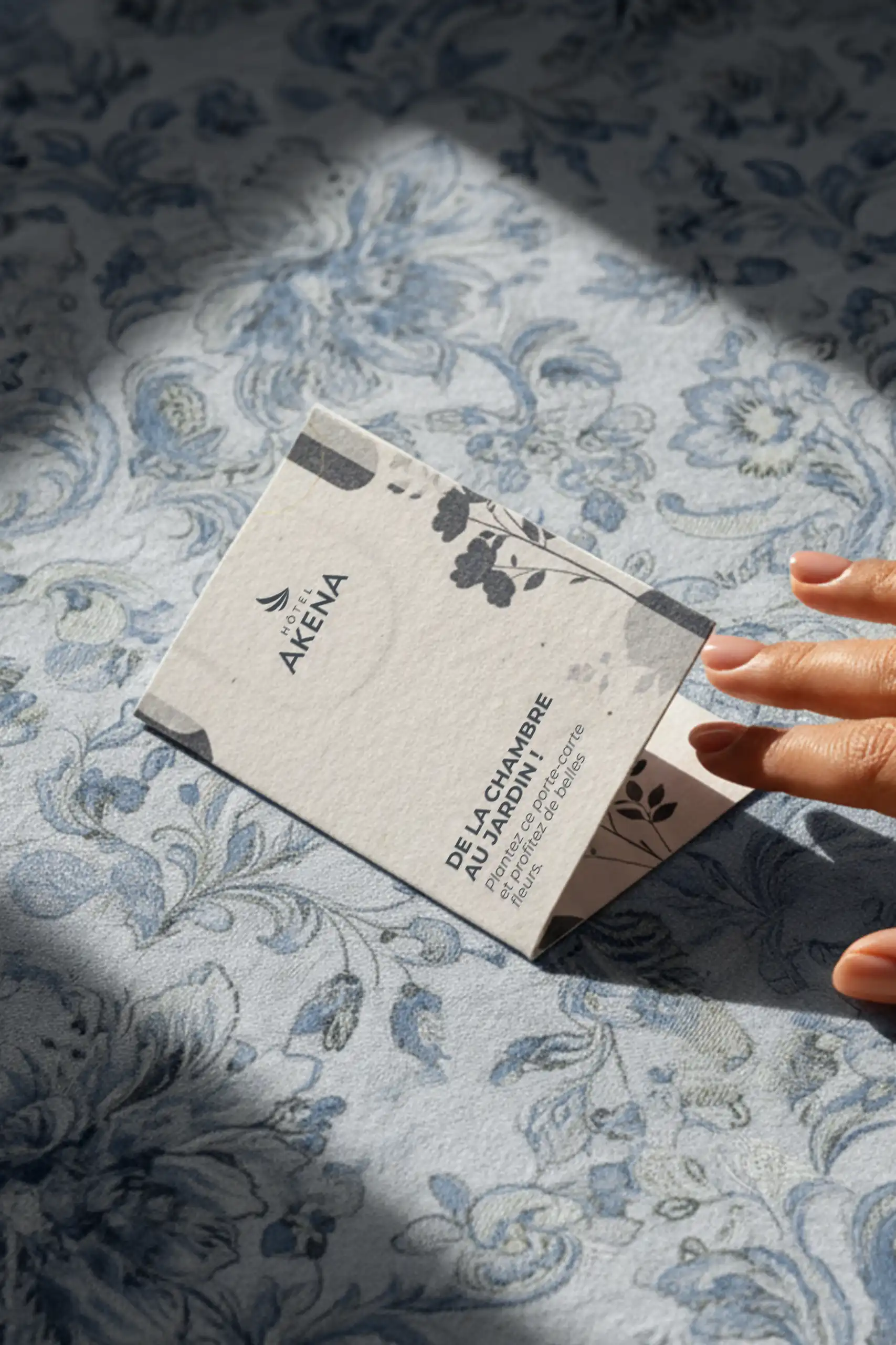 Mano abriendo un porta llaves de hotel de papel personalizado para el HOTEL AKENA 