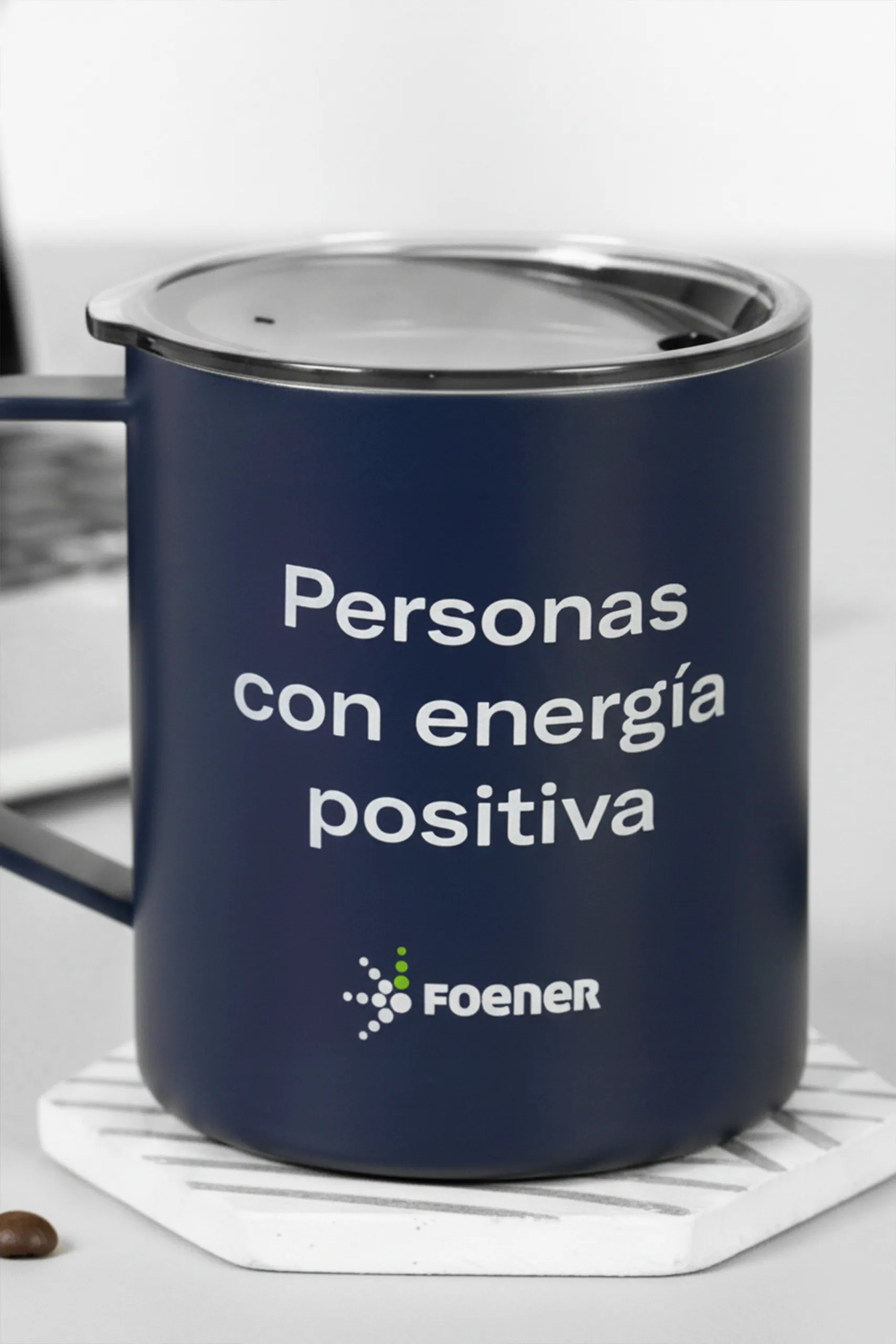 Taza térmica azul personalizada para la marca FOENER, sobre un posavasos blanco