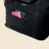 Detalle de un bolsillo exterior de una bolsa de viaje negra personalizada con la palabra 'logo' en blanco