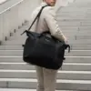 Chico subiendo unas escaleras llevando una bolsa de viaje negra personalizada con el logo de Sheedo en blanco