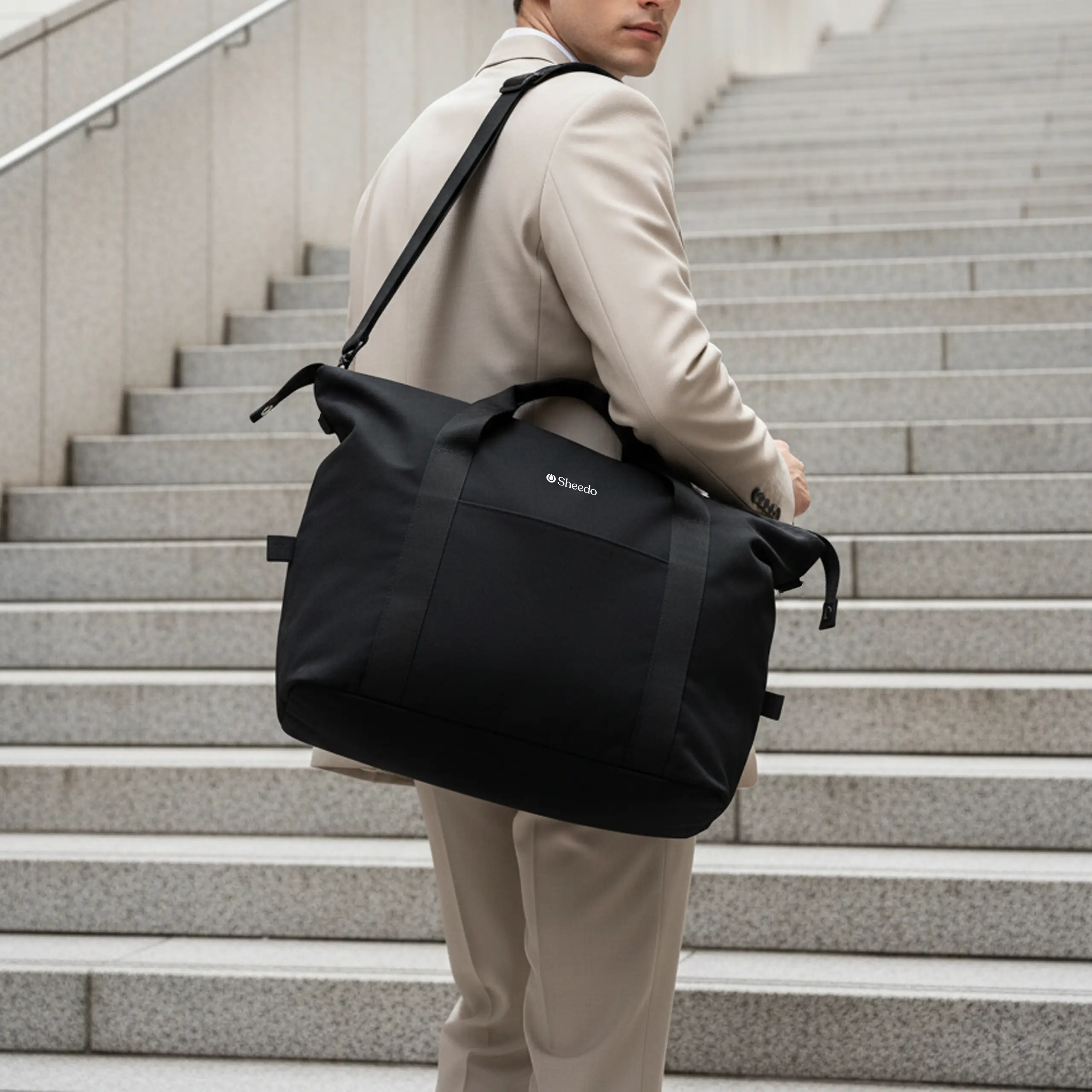 Chico subiendo unas escaleras llevando una bolsa de viaje negra personalizada con el logo de Sheedo en blanco